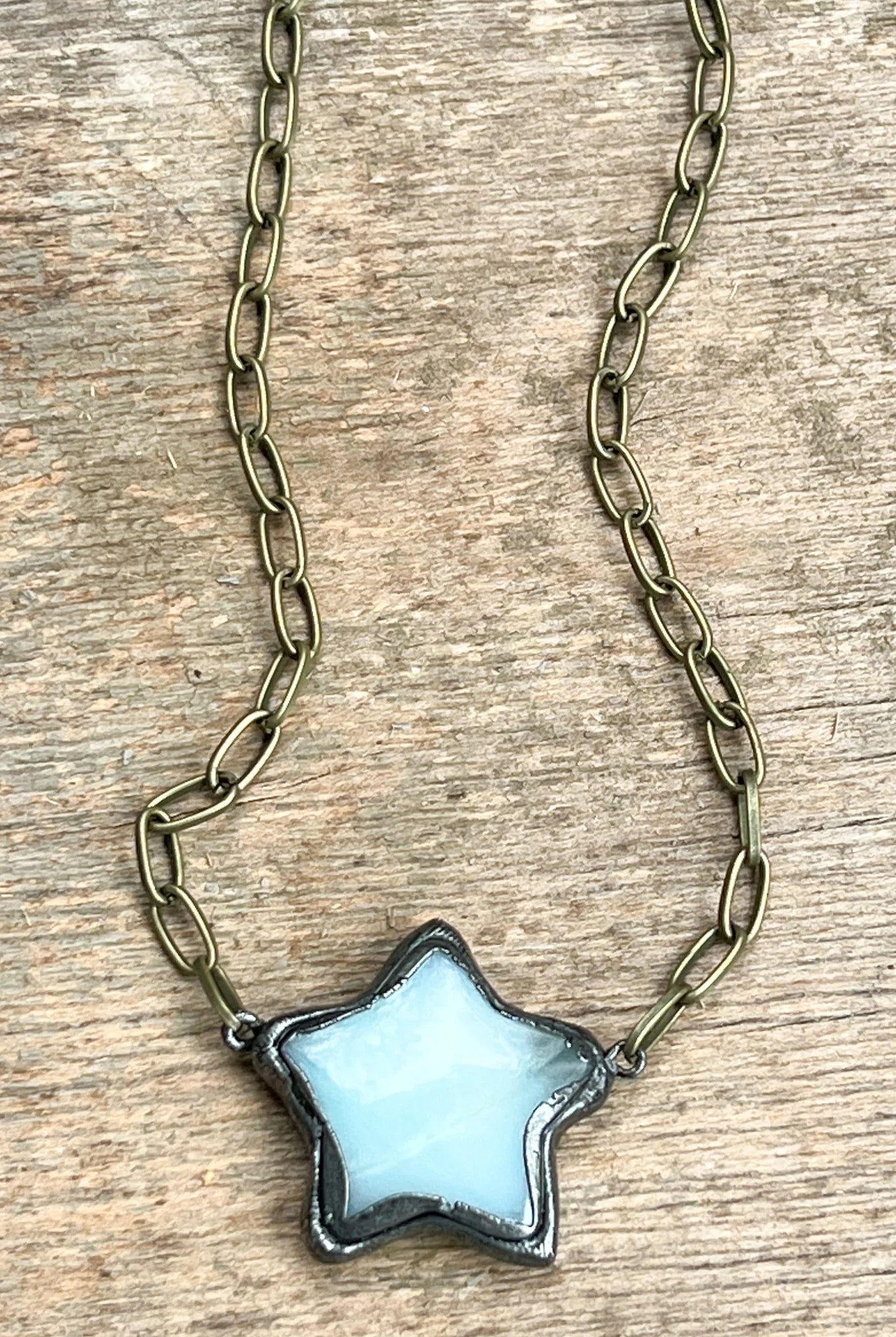 Star-shaped pendant on a chain against a wooden background