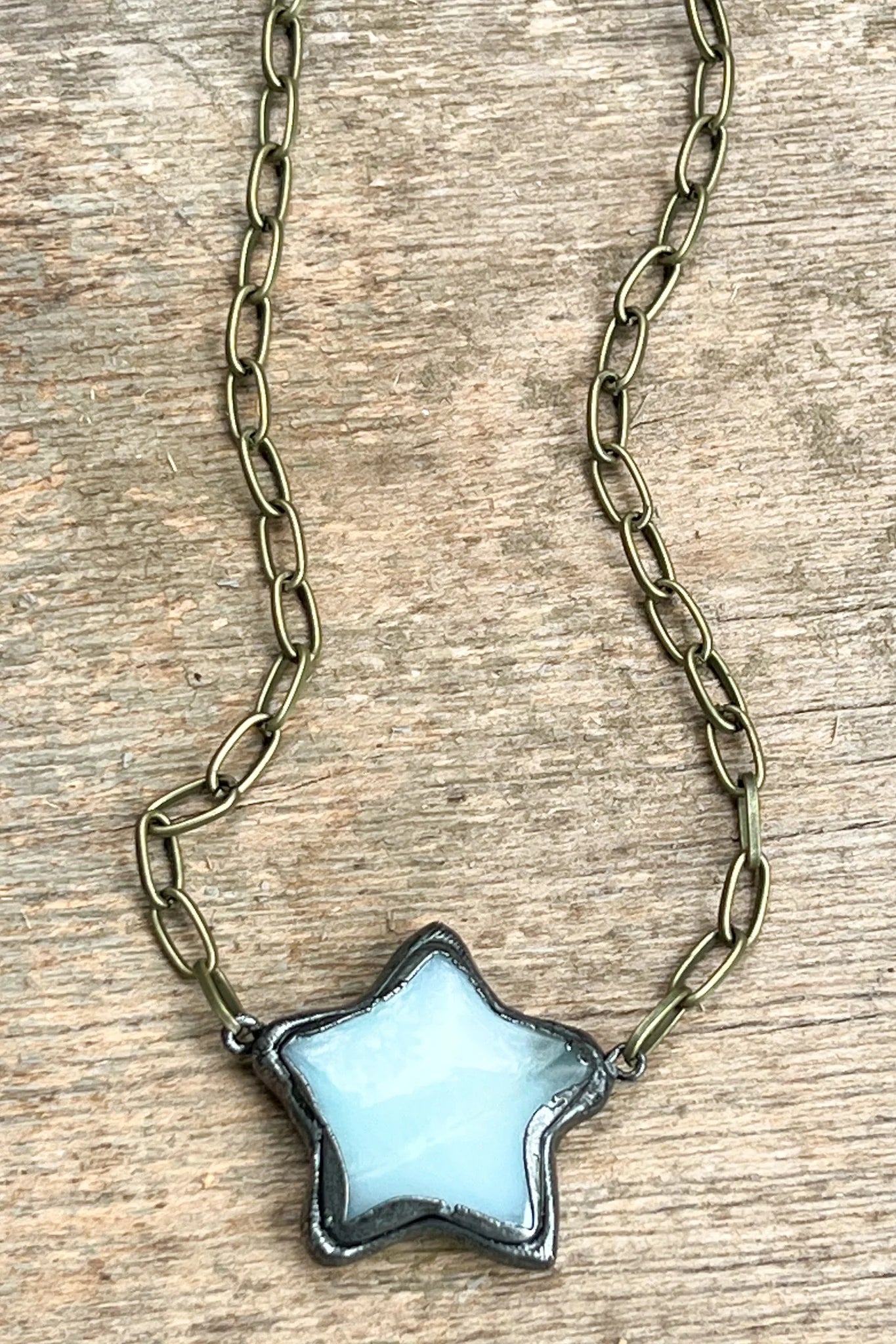 Star-shaped pendant on a chain against a wooden background