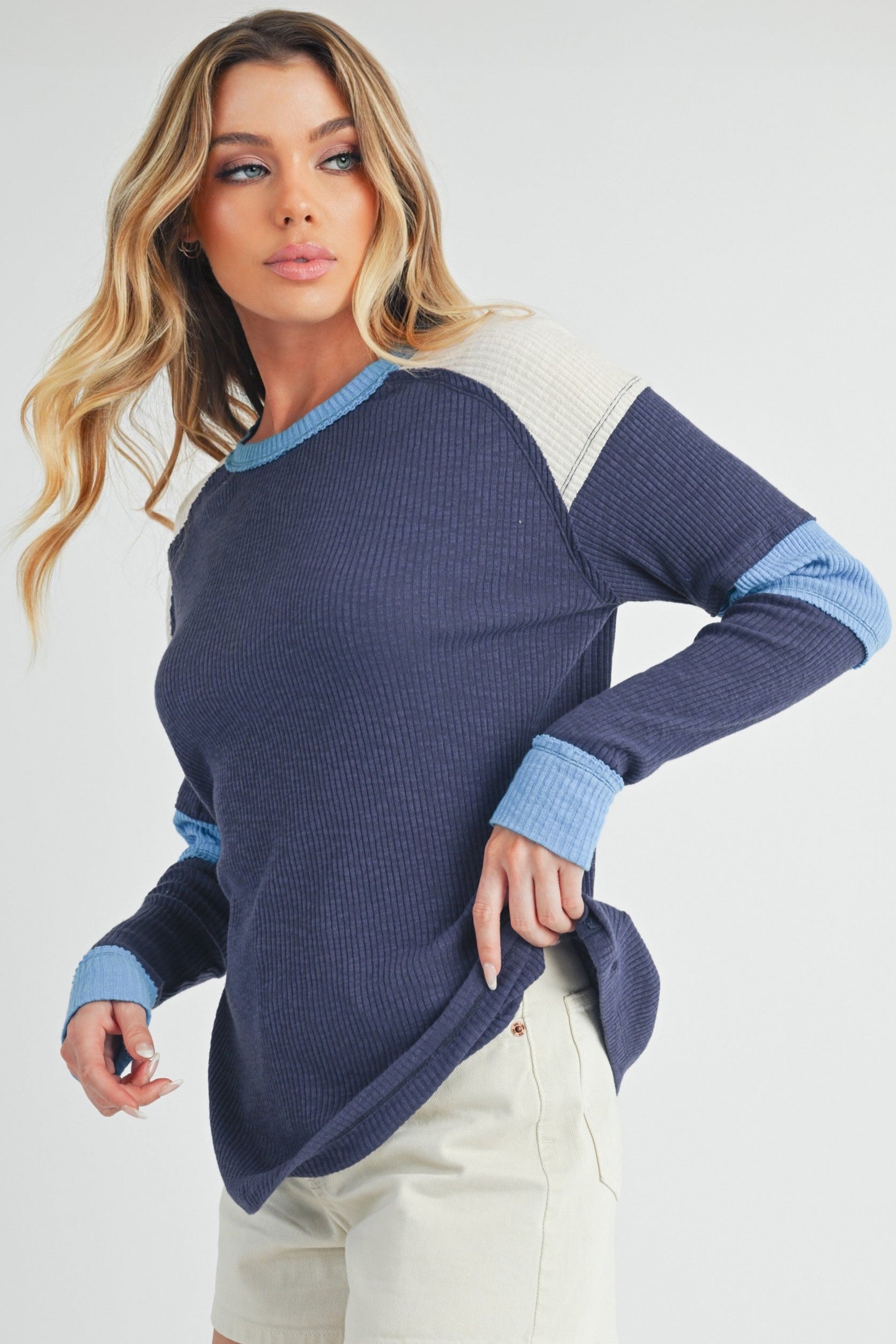 girl wearing a patchwork colorblock thermal top in blue and neutral tones.