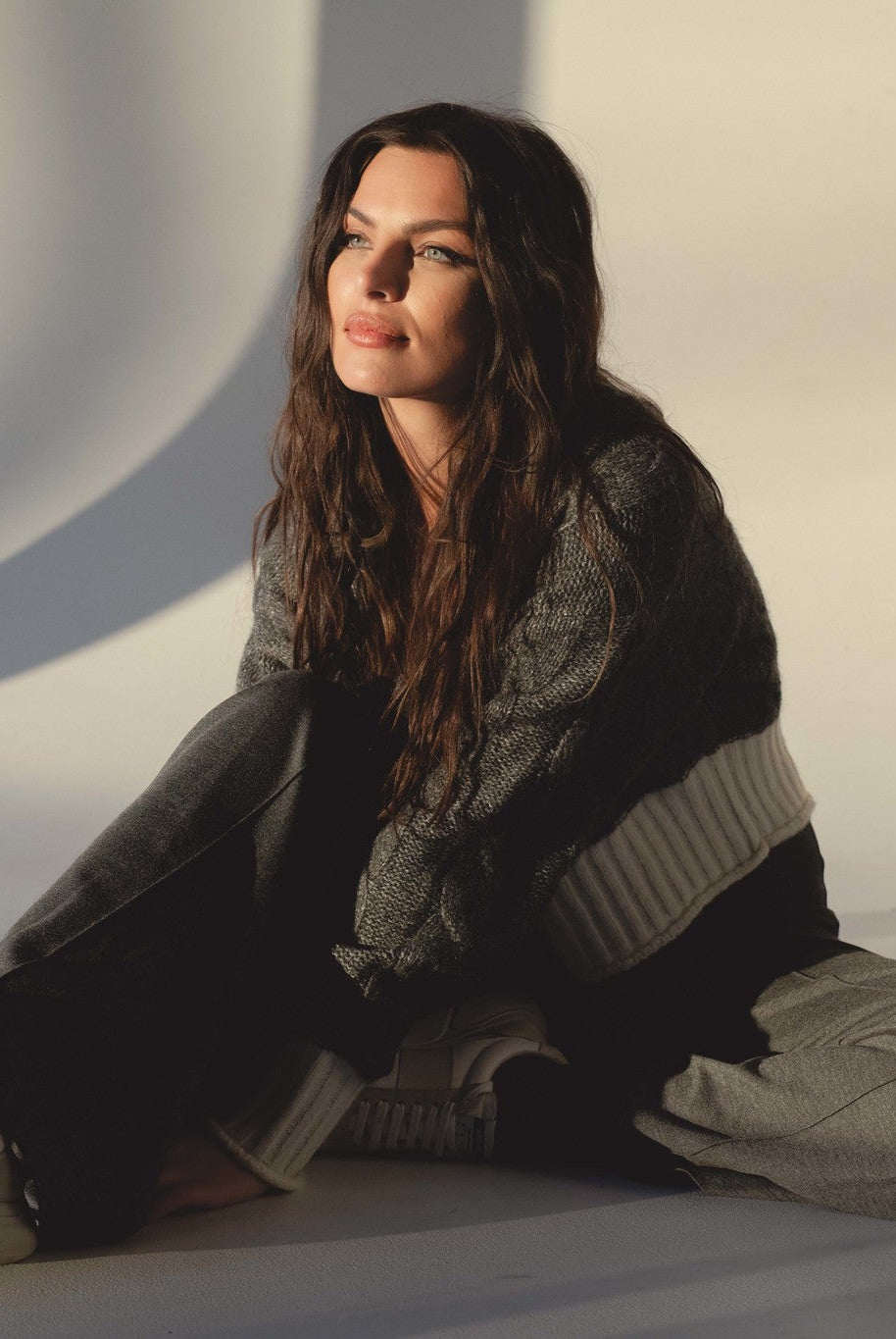 woman sitting on the ground wearing the grey and white cardigan and grey pants from Mainstream Bloomington