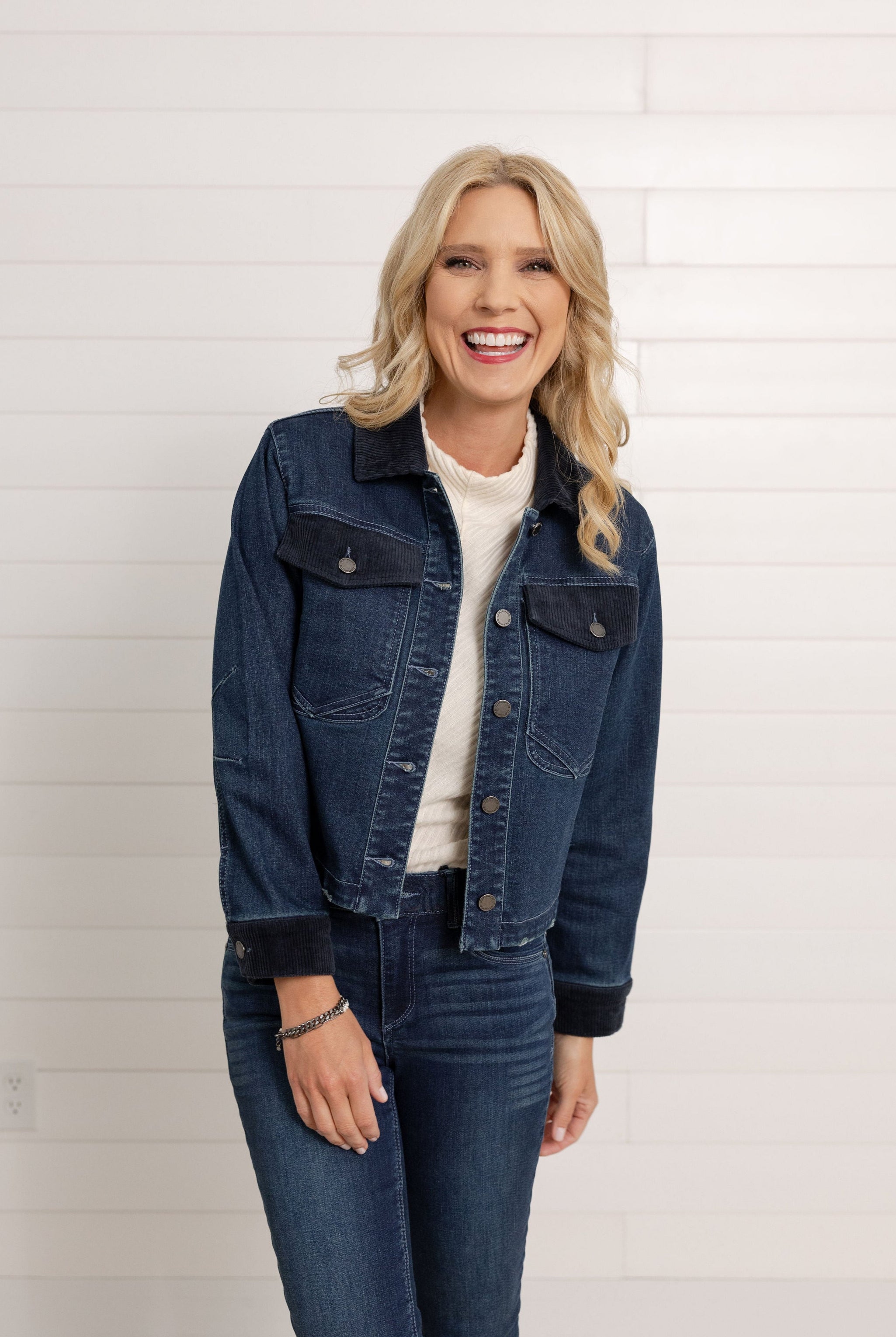 This woman is moving around in a dark denim Mac and Me Jacket with Pockets and corduroy details. She is also wearing the dark denim Mac and Me Boot Cut denim and the Mac and Me Funnel Tank Top in a cream color.