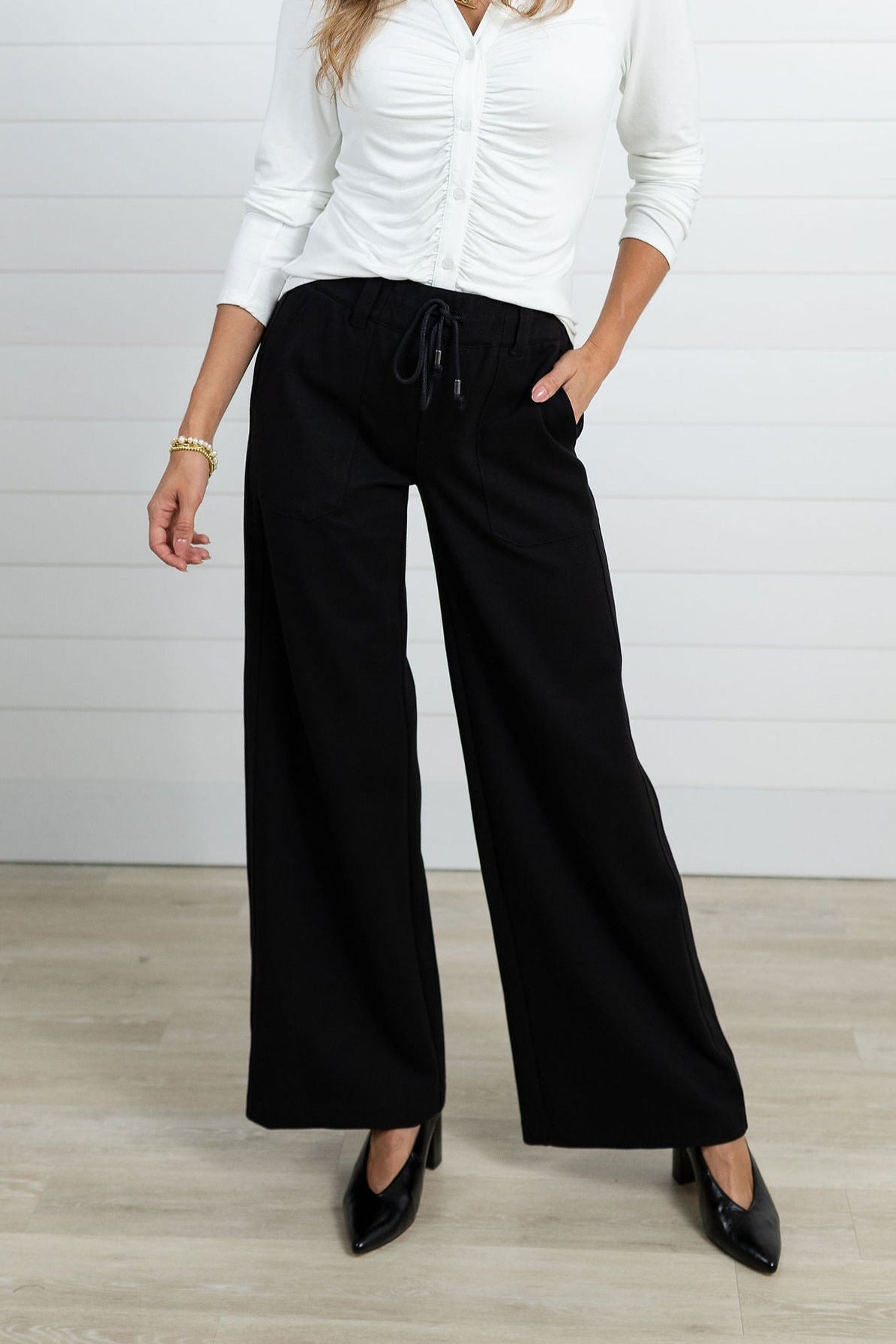 Woman modeling the Mac and Me black ponte trouser combined with the white ruched top from Mac and Me.