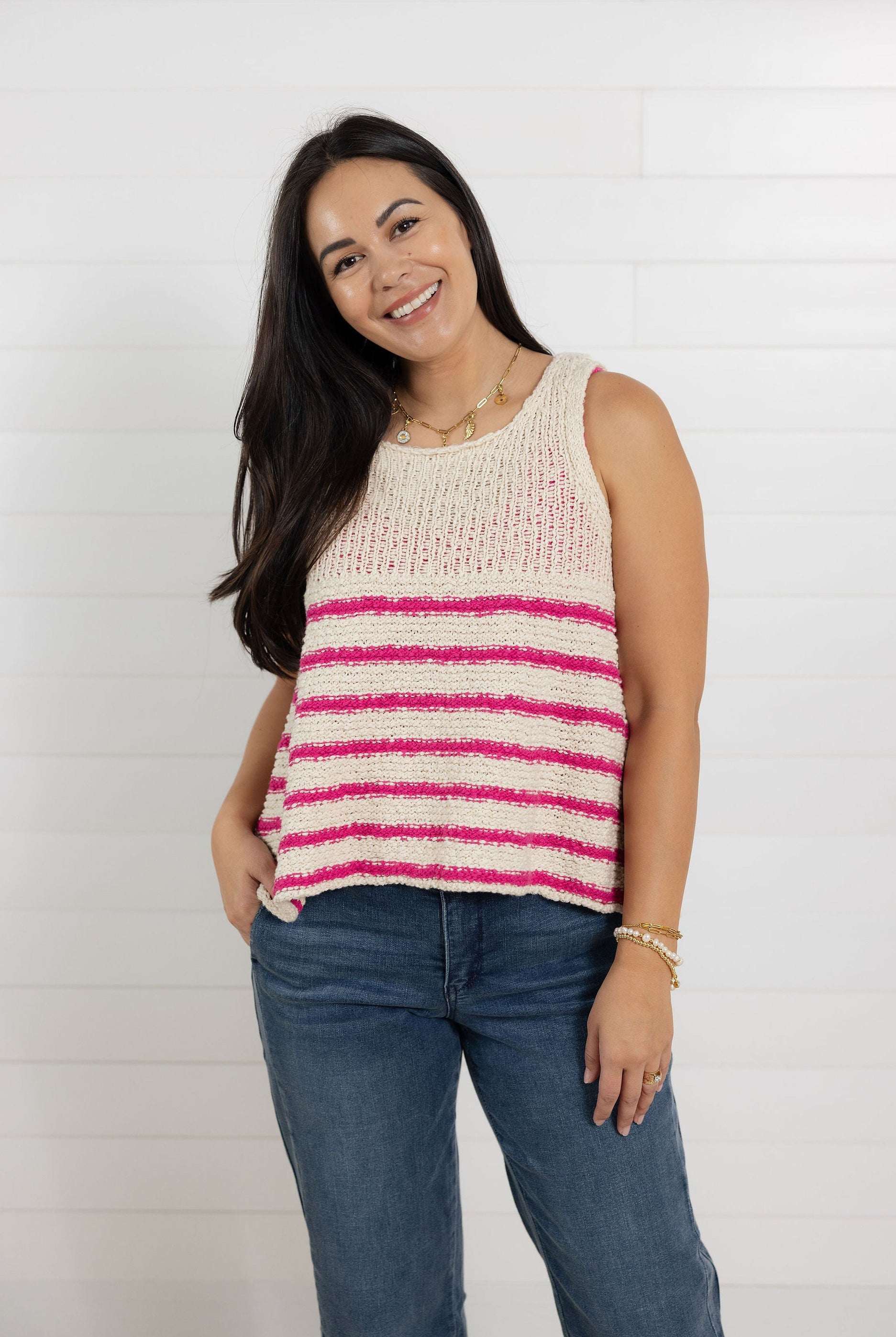 Woman wearing a sleeveless striped top and jeans against a white background