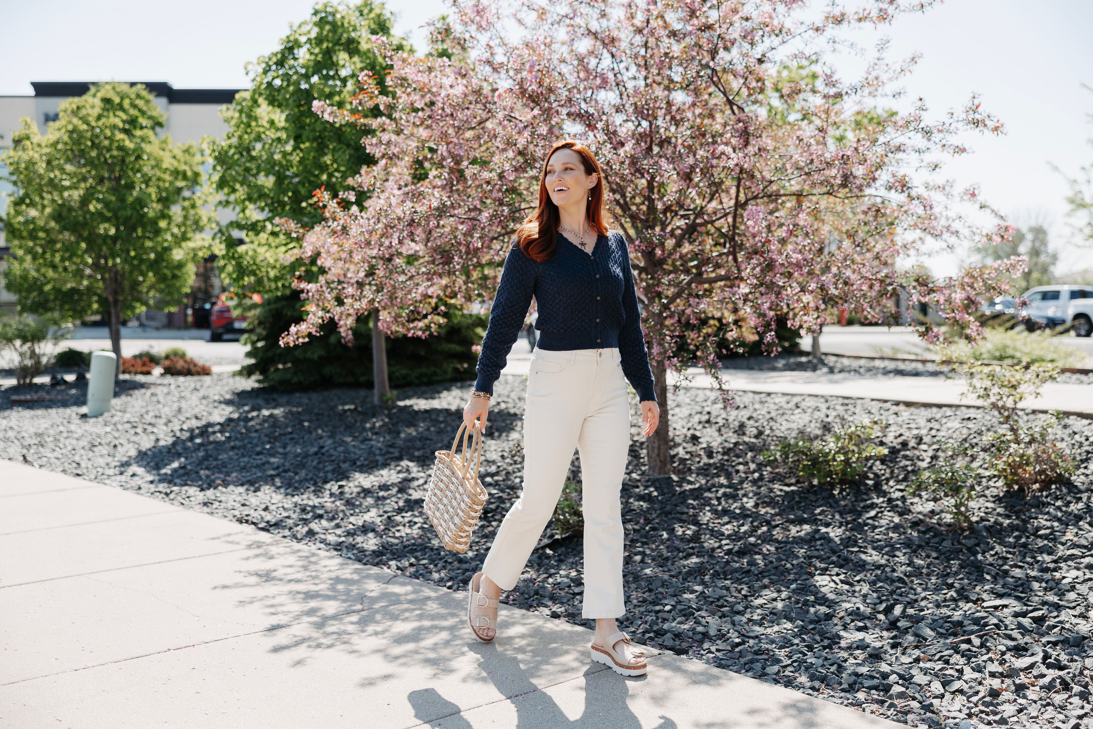 Customer walking outside on a sunny day in a new rose button navy sweater fresh and ready for Fall 2025!