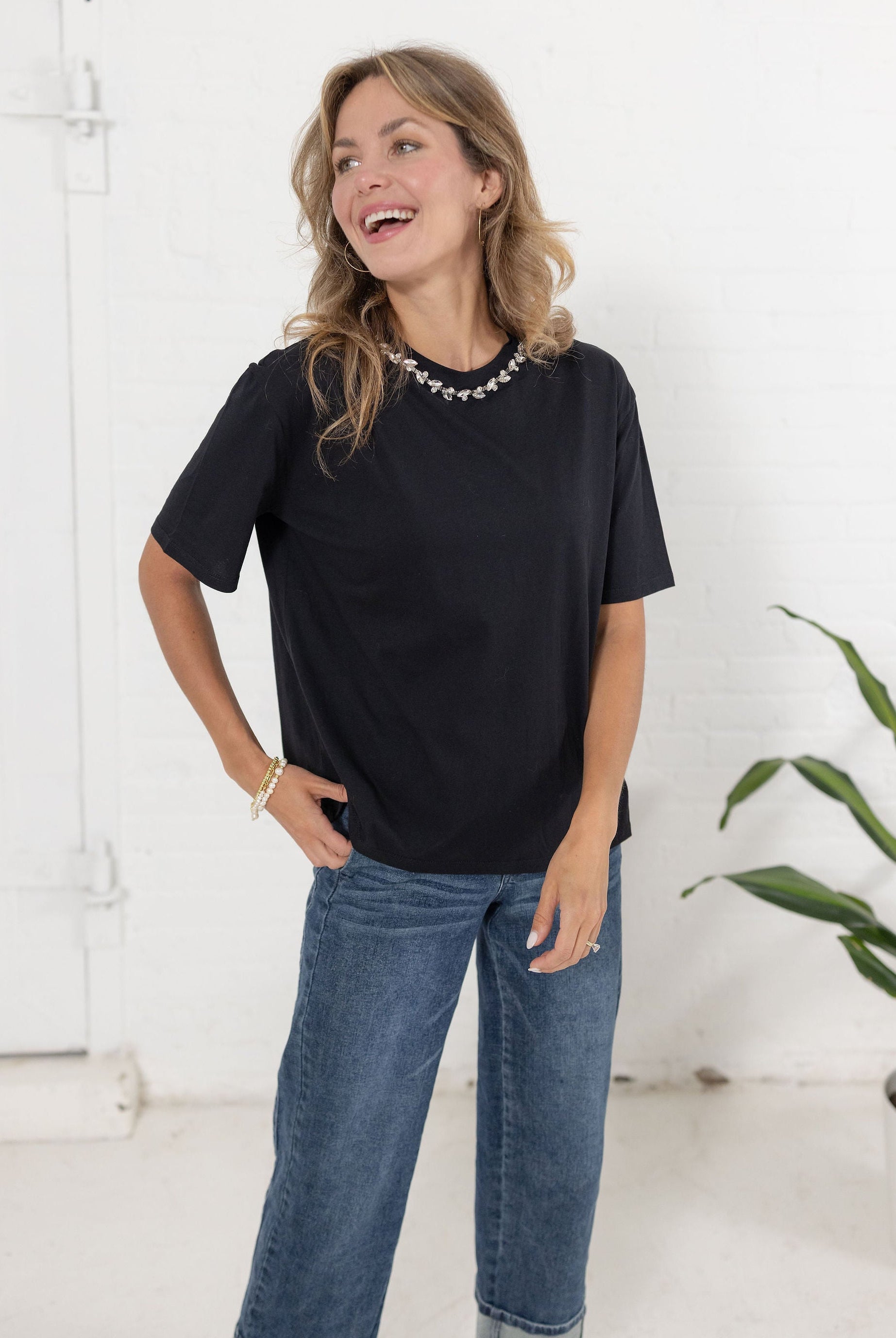 Model wearing The Soirée Tee in black with rhinestone embellished neckline from Mainstream Boutique Bloomington