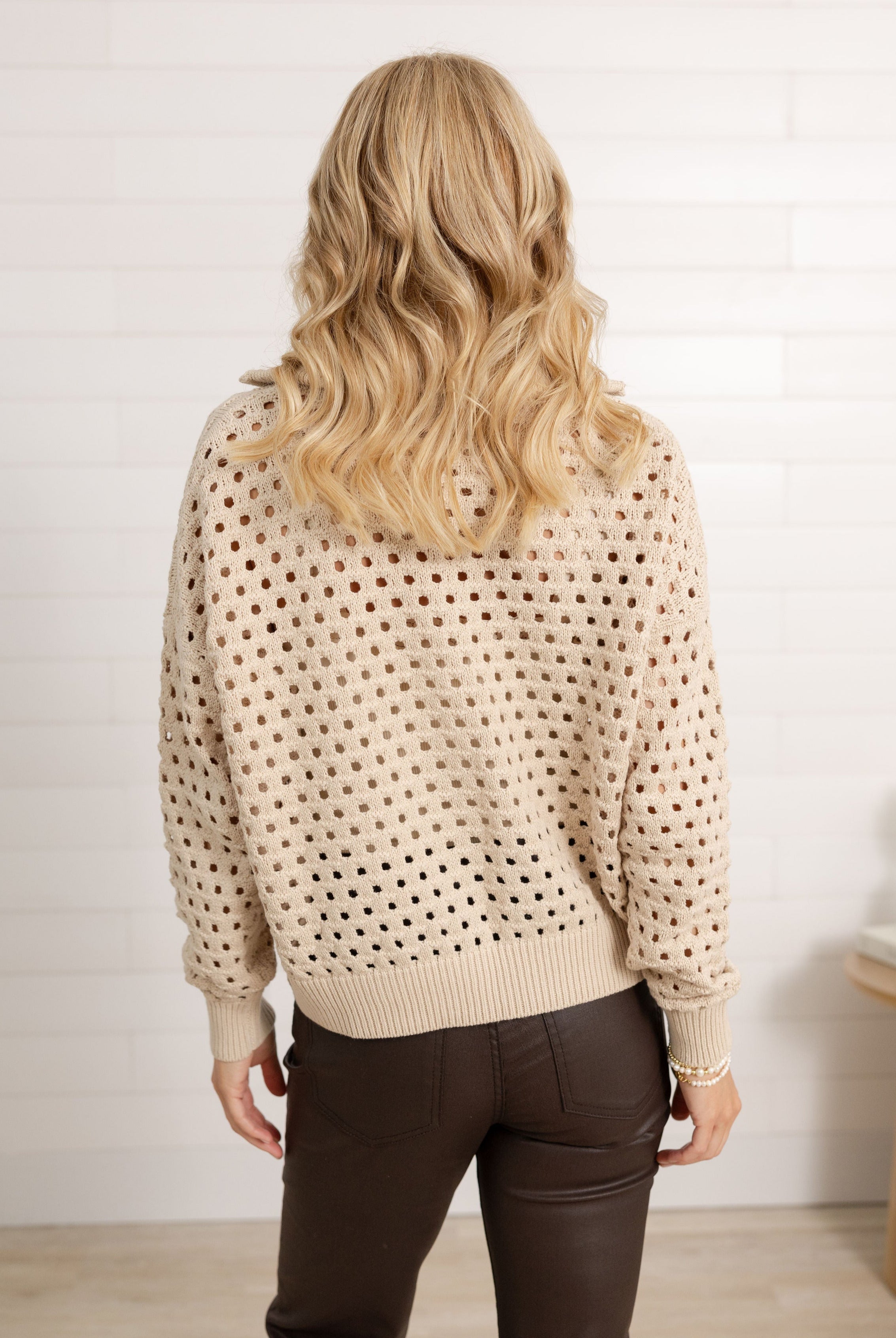 Woman showing the back side of the open knit sweater from Mainstream Boutique Bloomington.