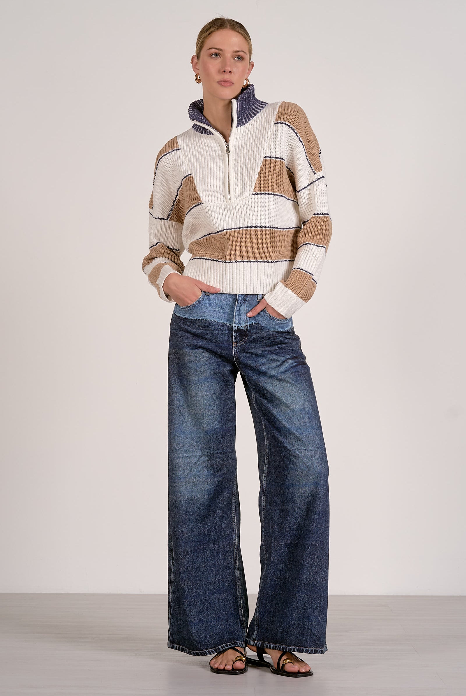 Woman wearing a striped half zip sweater in camel white and blue with fold-down collar and sweatpant jeans
