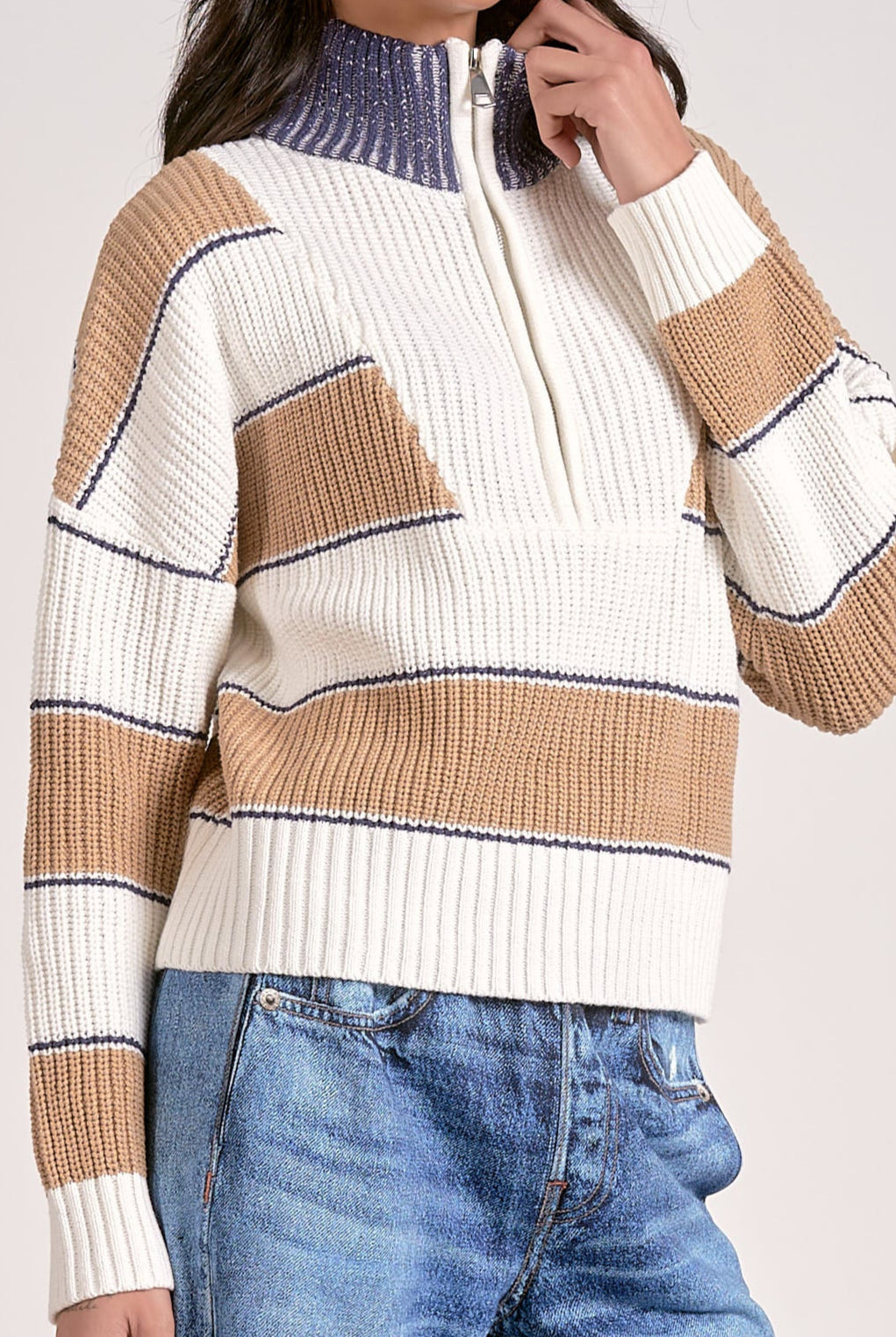 Woman showing close up of the striped half zip sweater in camel, white, and blue