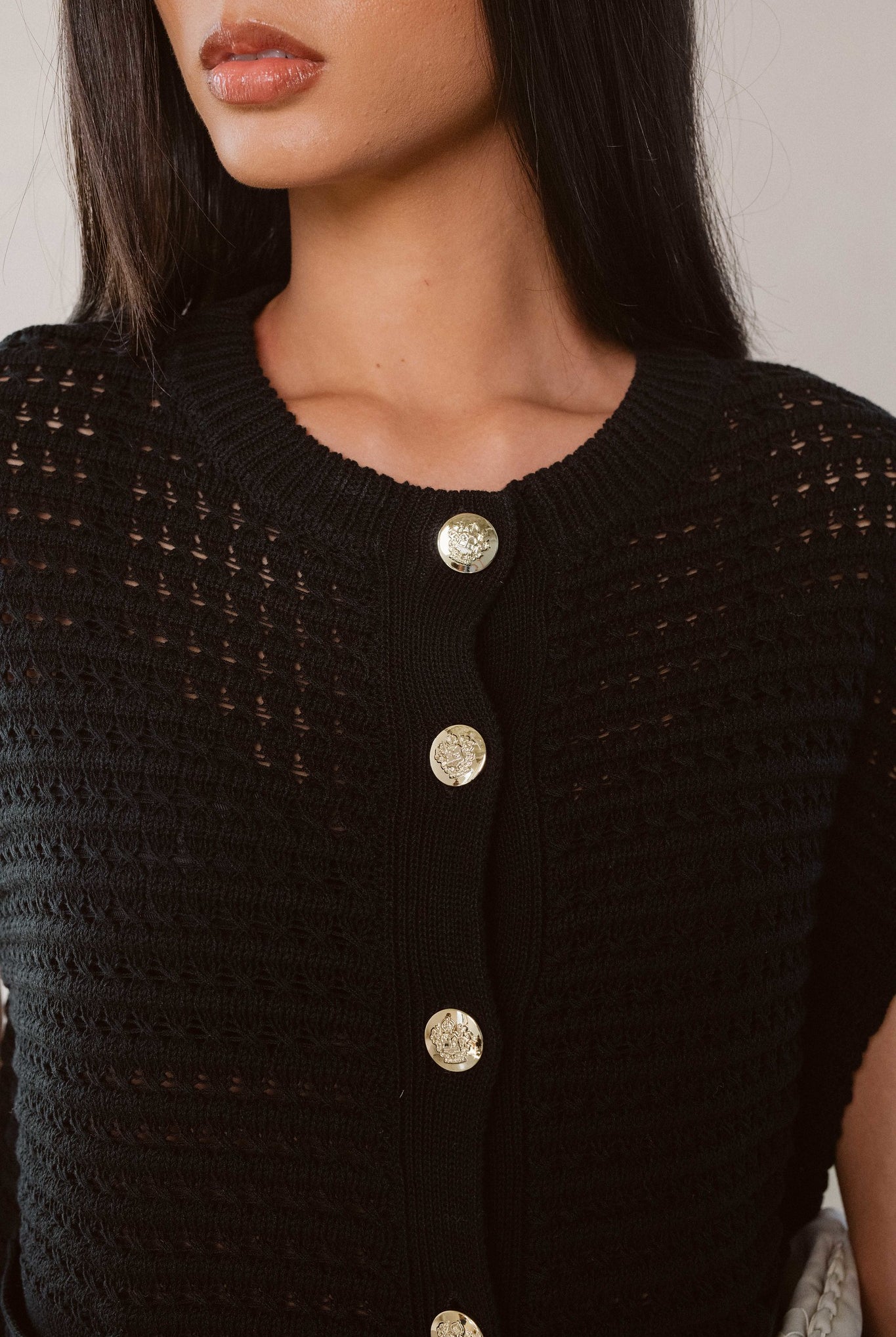 Woman showing the button and knit details on the black button cardigan