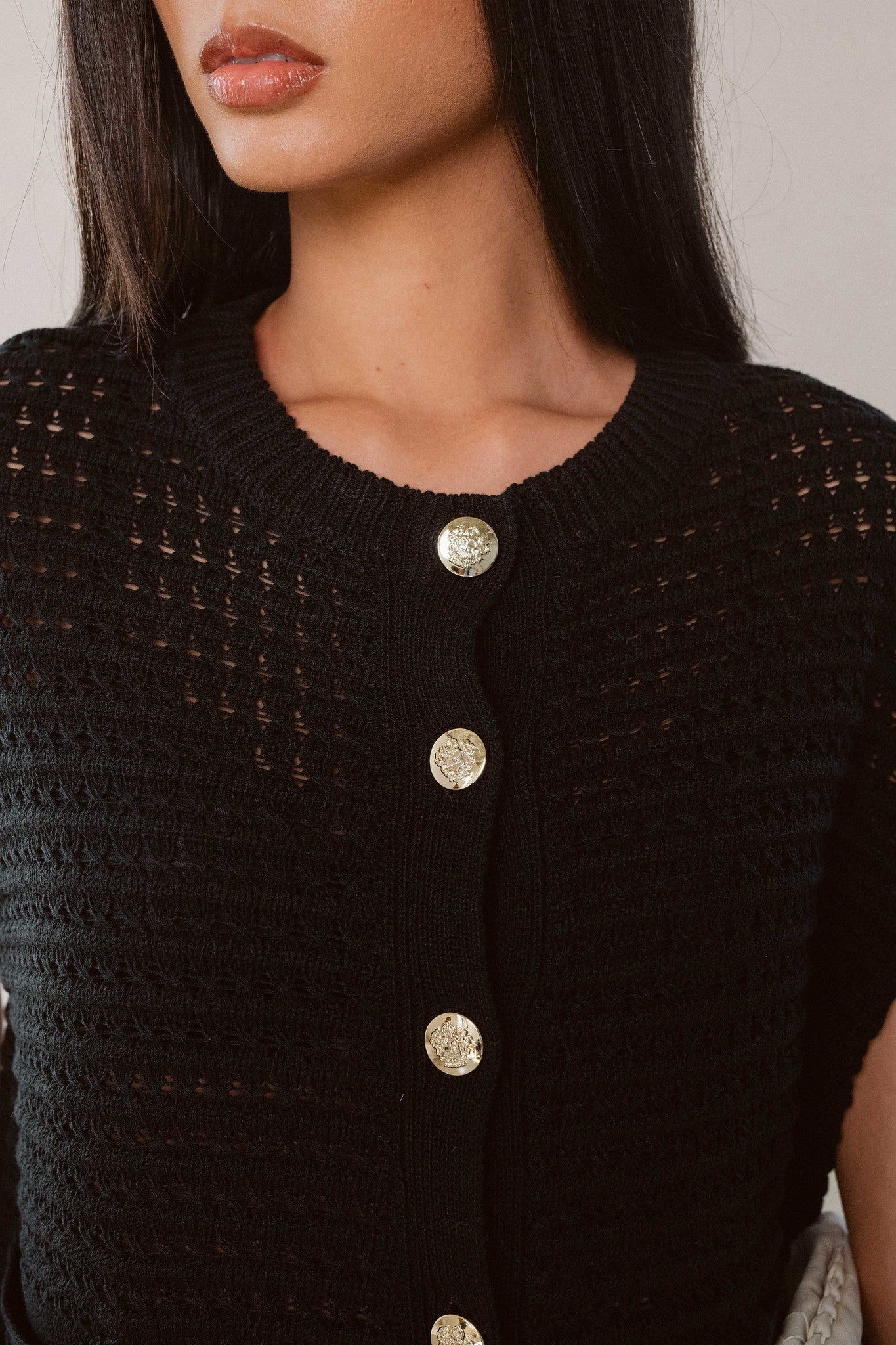Woman showing the button and knit details on the black button cardigan