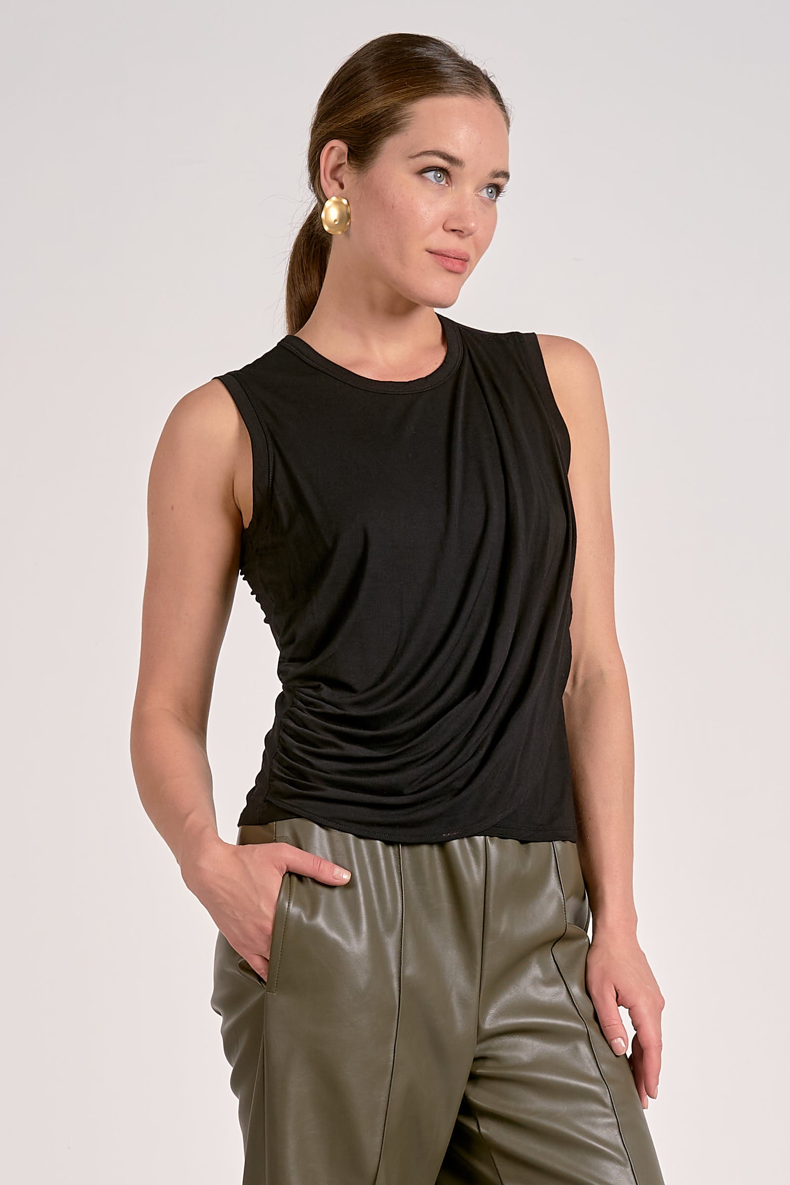 Woman wearing black draped sleeveless top with flattering side drape in a lightweight knit
