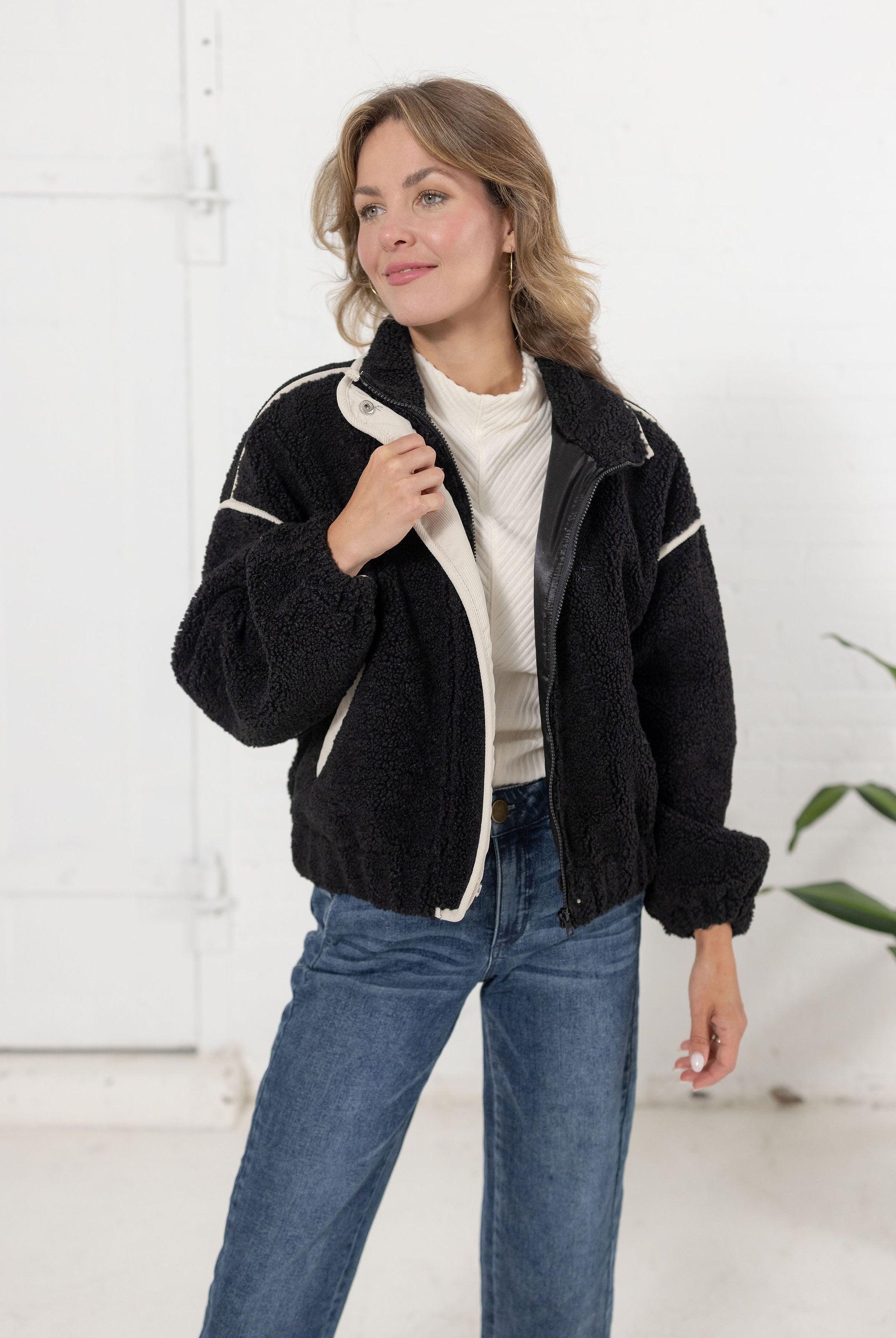 woman wearing the black sherpa bomber jacket in black with off white corduroy contrast trim