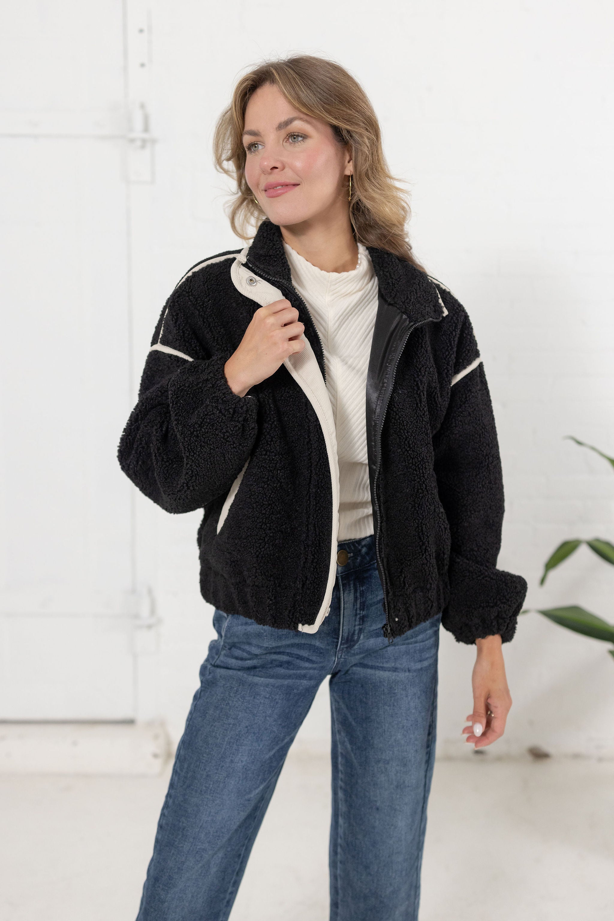 woman wearing the black sherpa bomber jacket in black with off white corduroy contrast trim