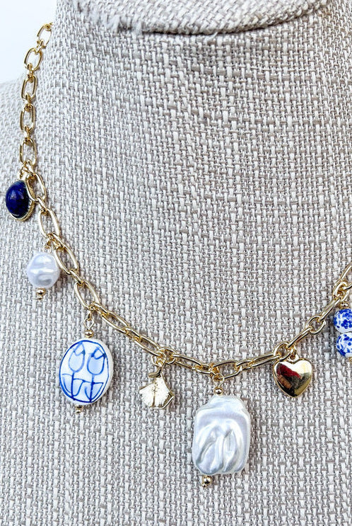 close up of blue and white porcelain charm necklace on gold chain