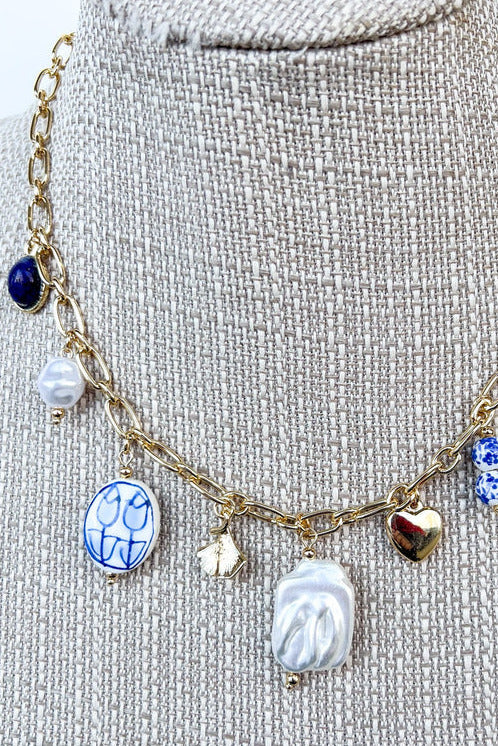 close up of blue and white porcelain charm necklace on gold chain