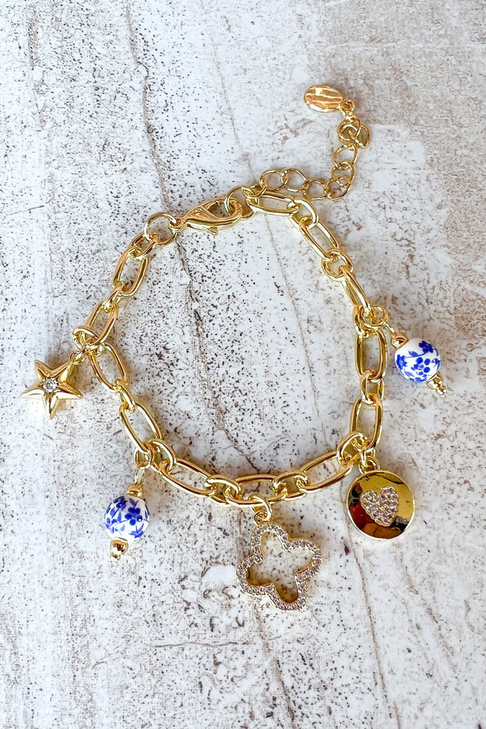 Gold chain bracelet with blue and white beads on a textured surface