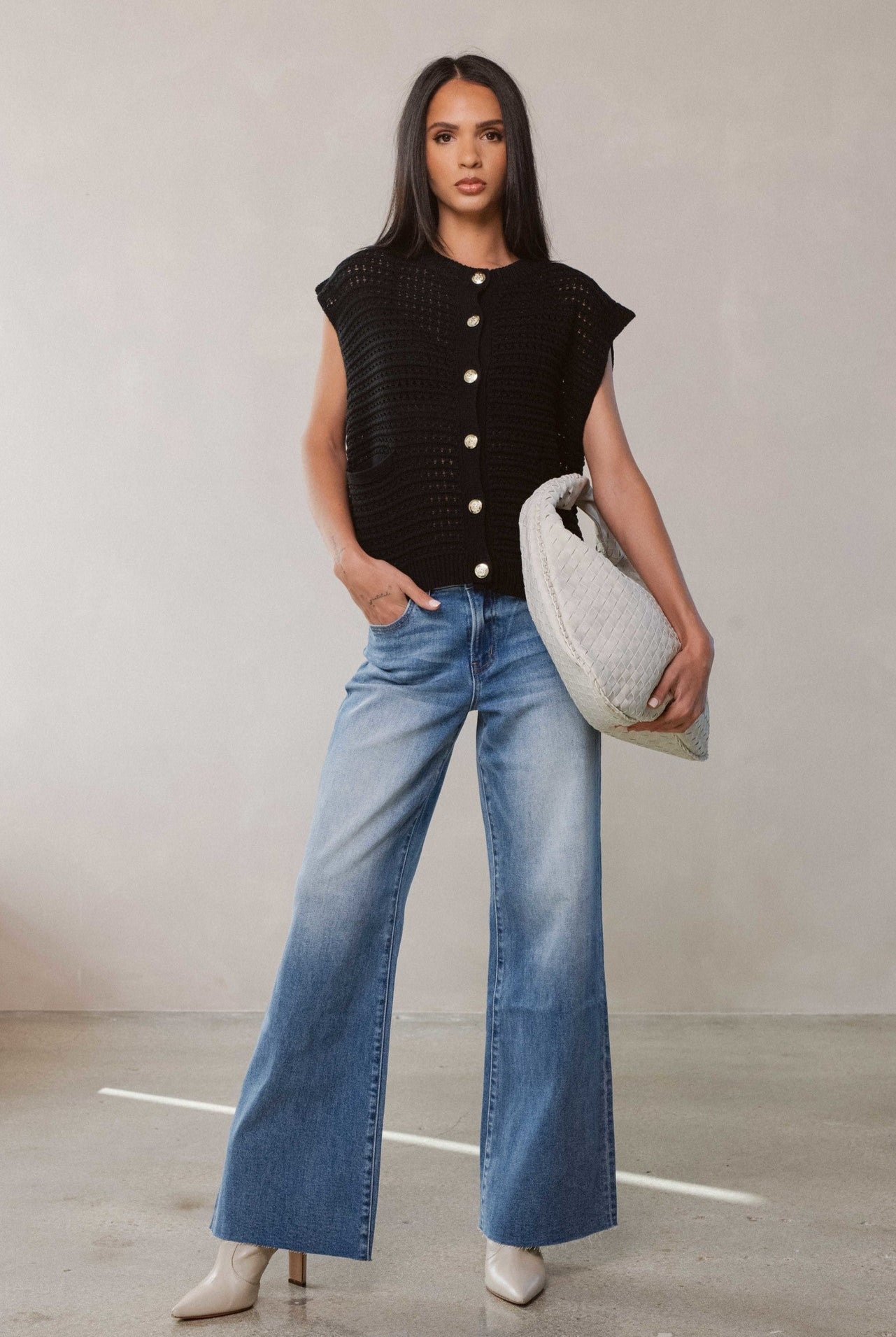 Woman modeling the button front cardigan in black along with light blue denim