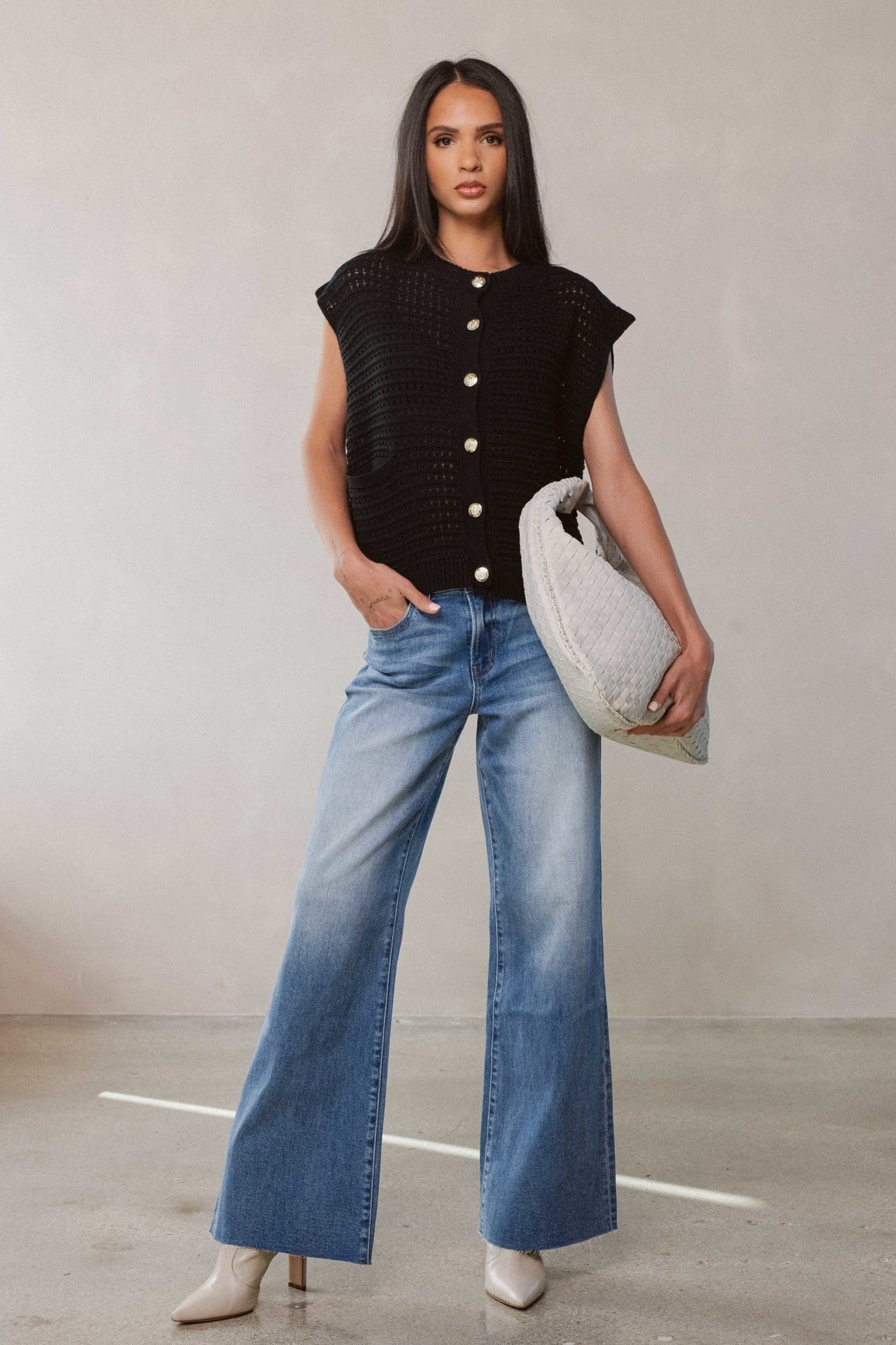 Woman modeling the button front cardigan in black along with light blue denim