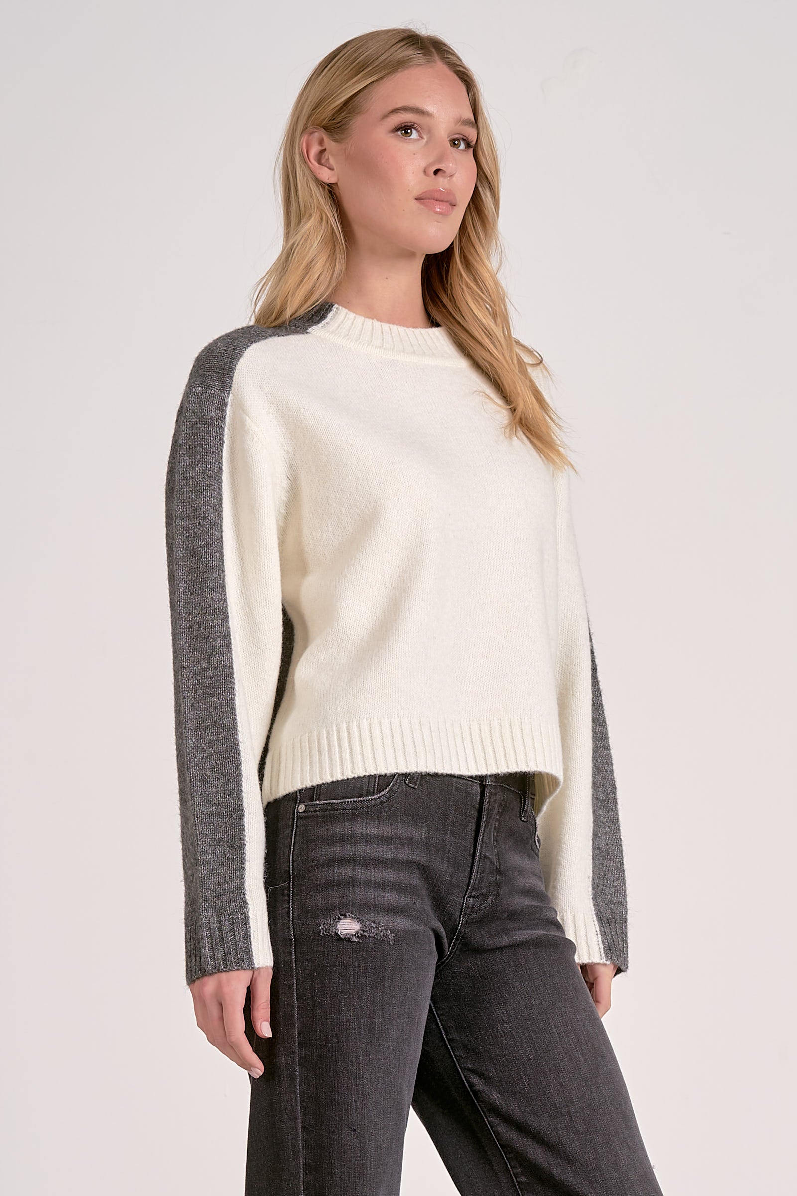 Side view of white and grey color block crewneck sweater with soft knit and stripe sleeve effect