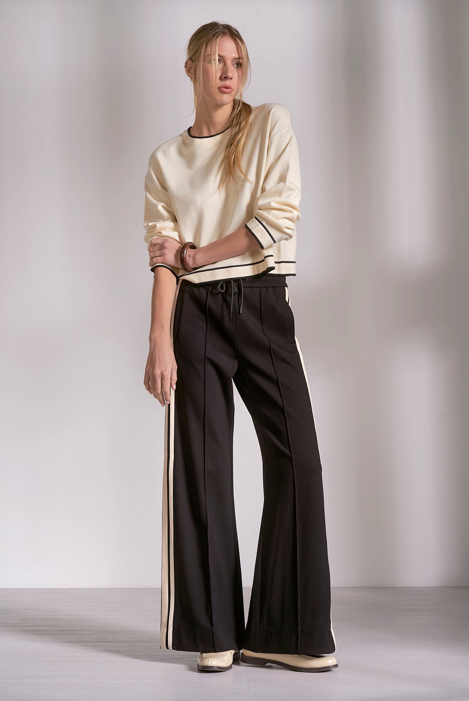 front of black wide leg track pants with natural stripe and drawstring waist