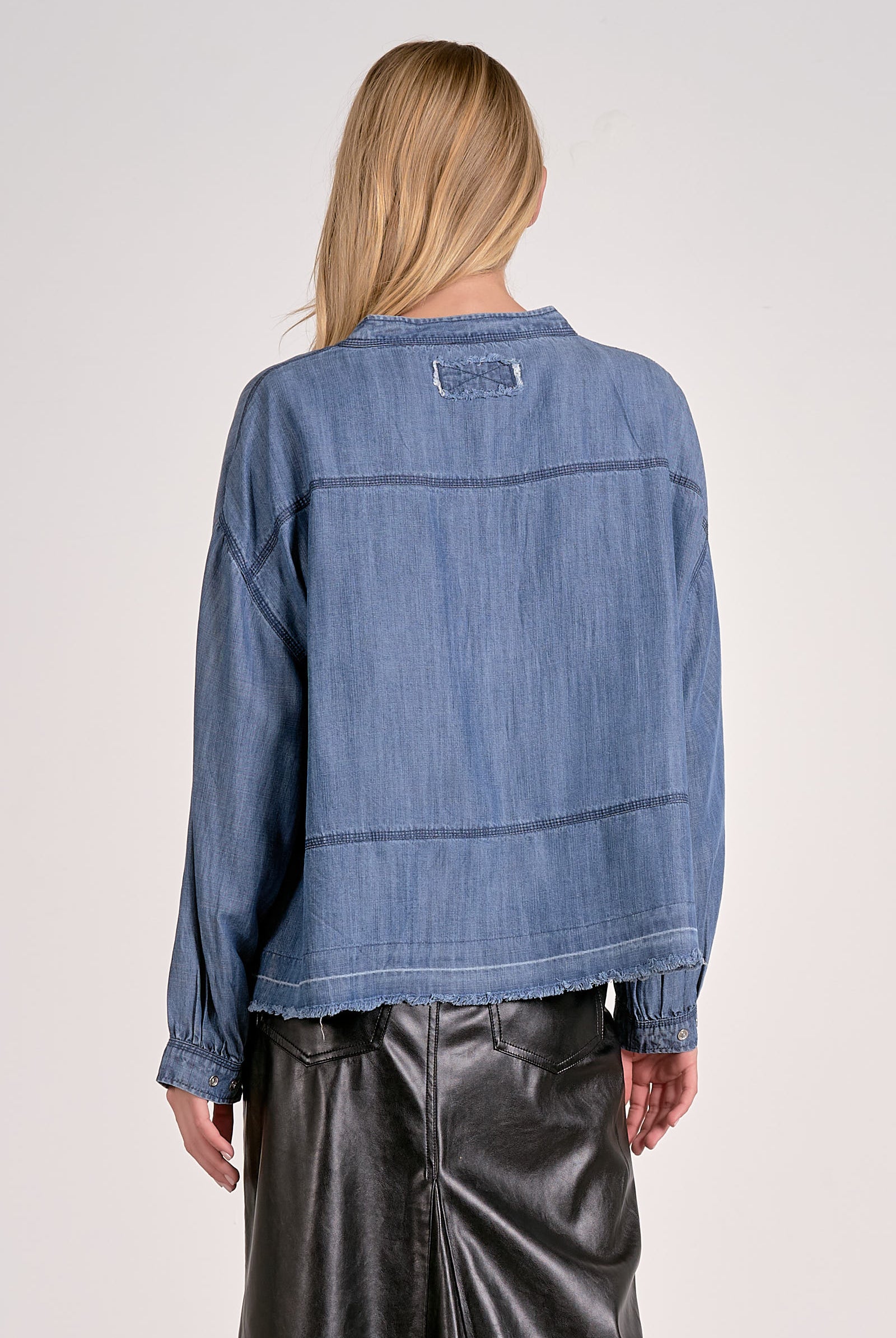 Back view of washed denim V-neck pullover showing long sleeves, relaxed fit, and frayed hem