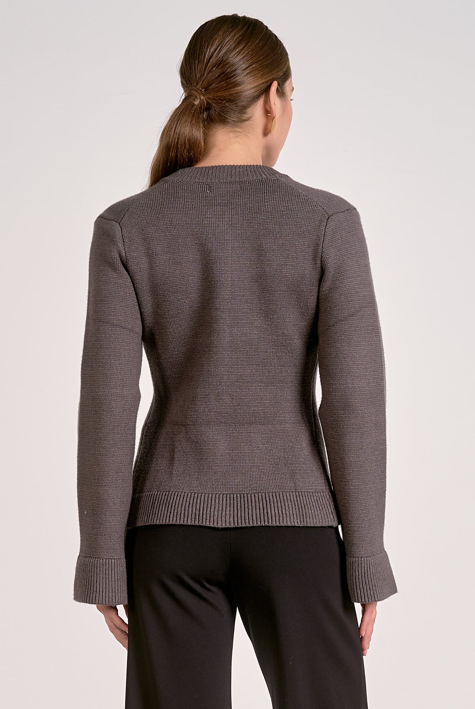 Woman showing the back view of the graphite flare cuff button cardigan front view