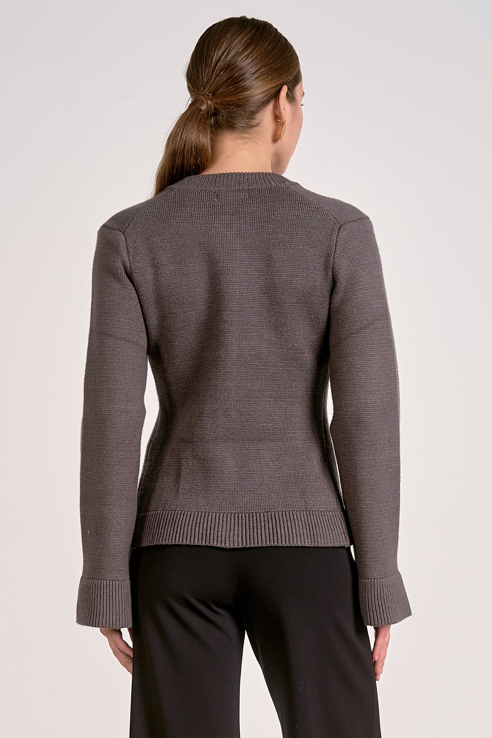 Woman showing the back view of the graphite flare cuff button cardigan front view