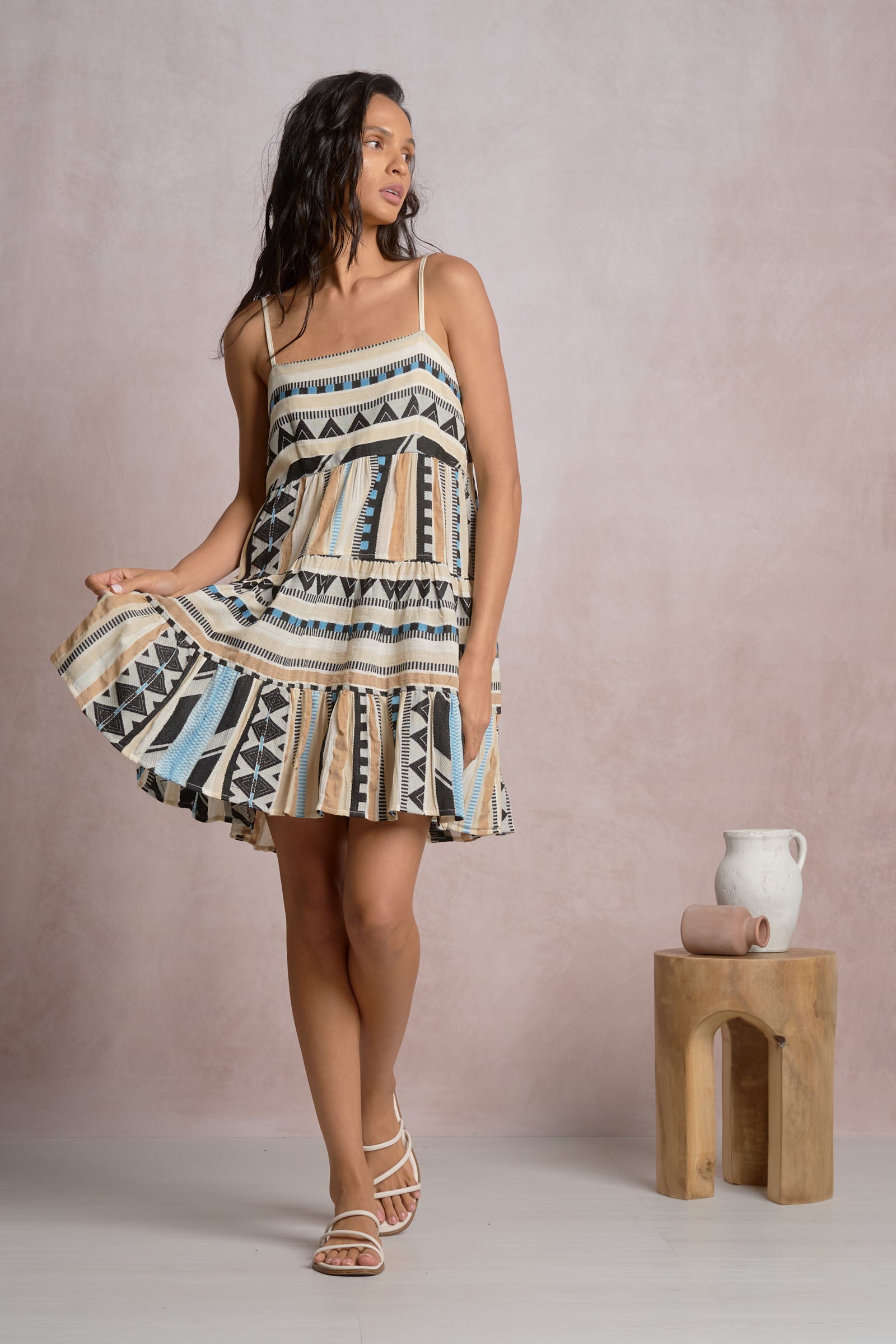 Woman wearing geometric stripe tiered mini dress with adjustable spaghetti straps