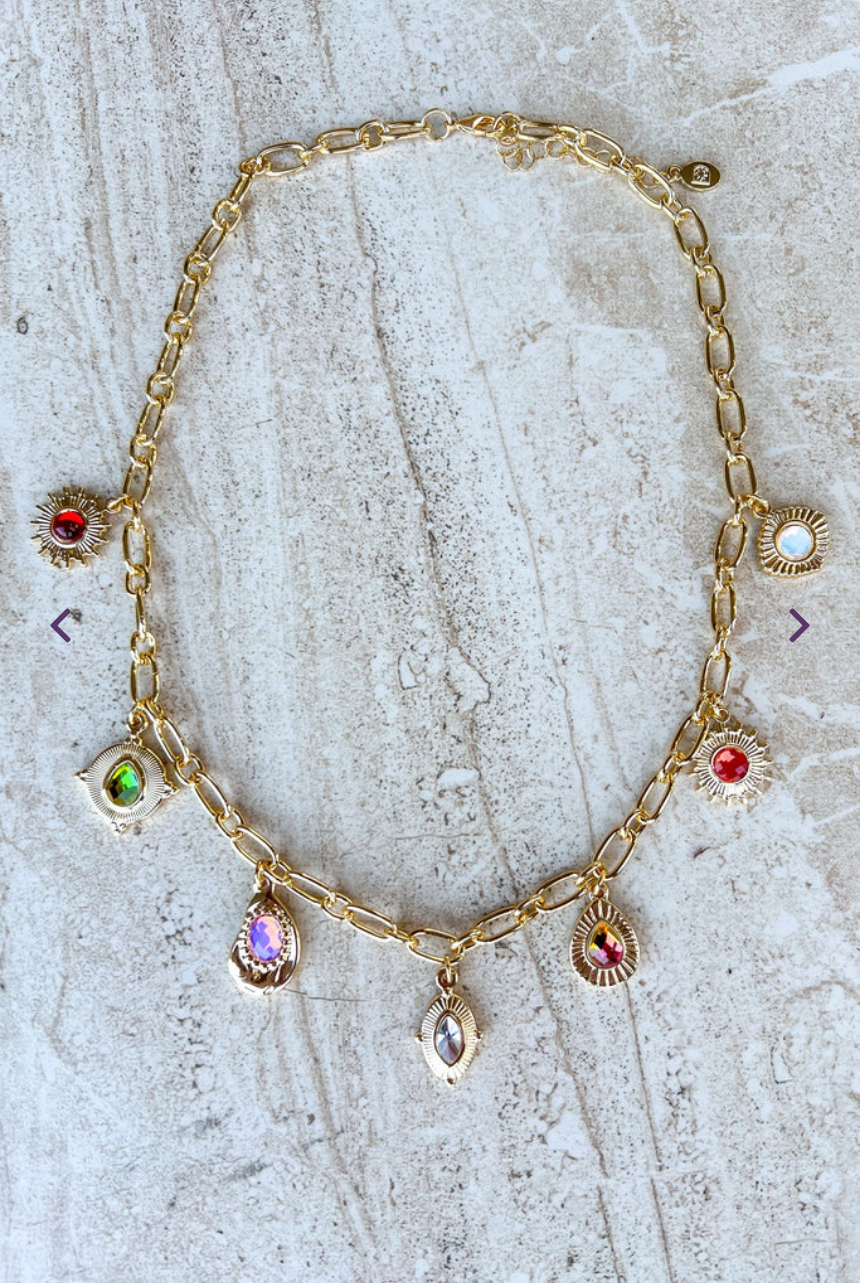Gold necklace with gemstone pendants on a textured surface
