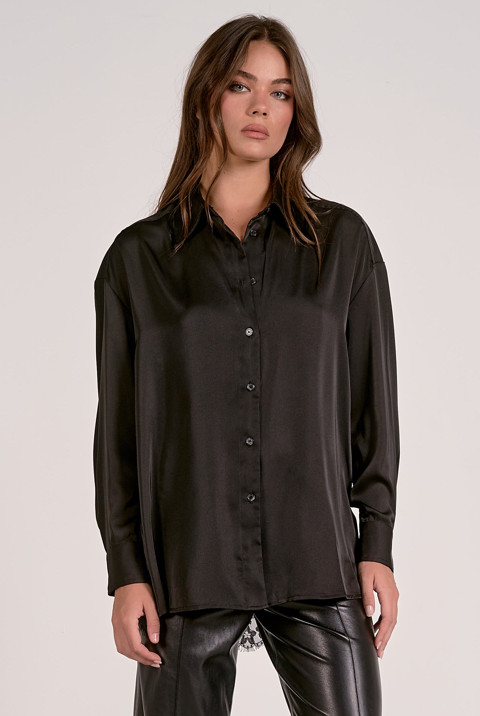 Model showing the front of the black satin button down blouse with lace back detail