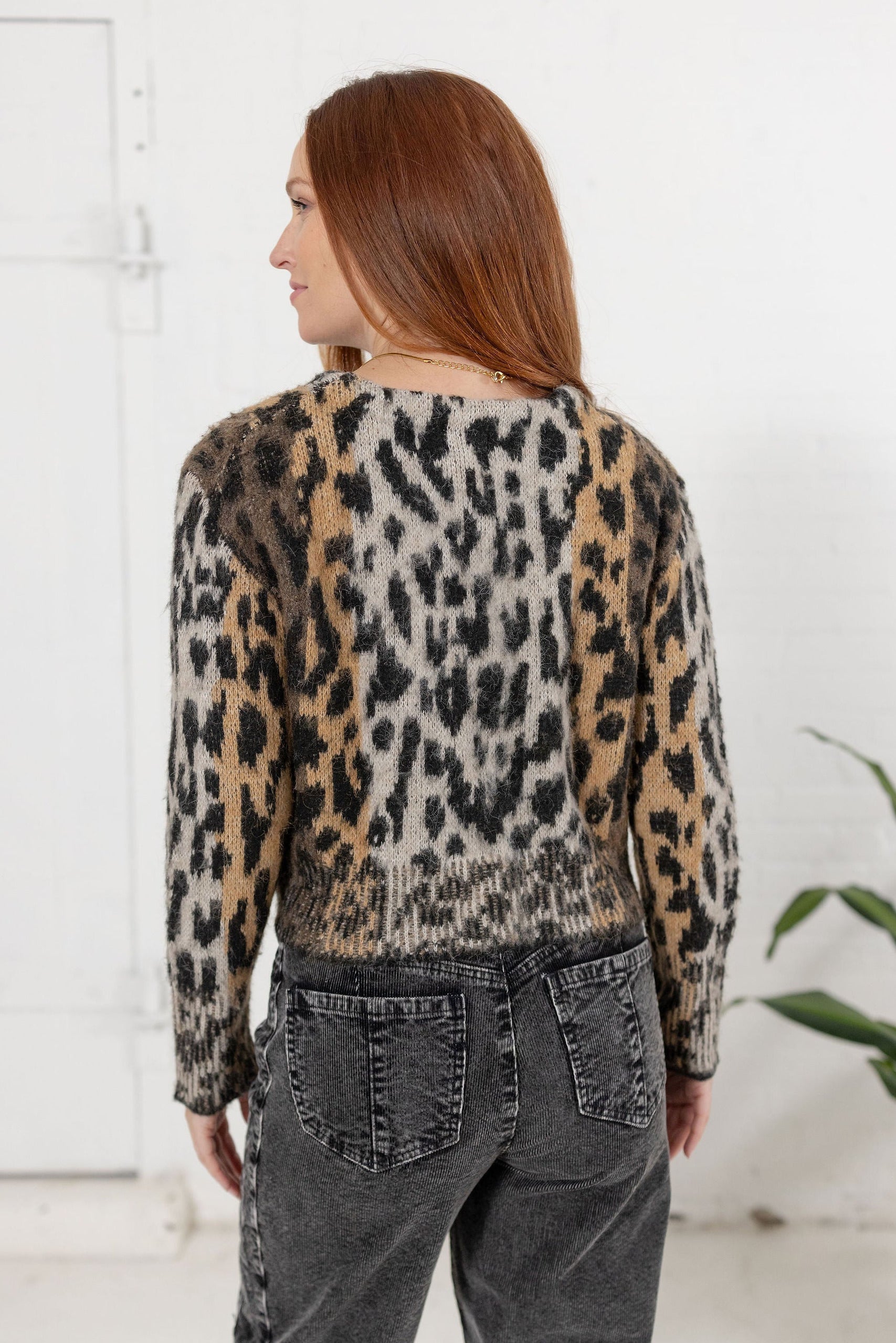 Woman modeling the back of the Meet & Greet Eyelash Cardigan in leopard print.