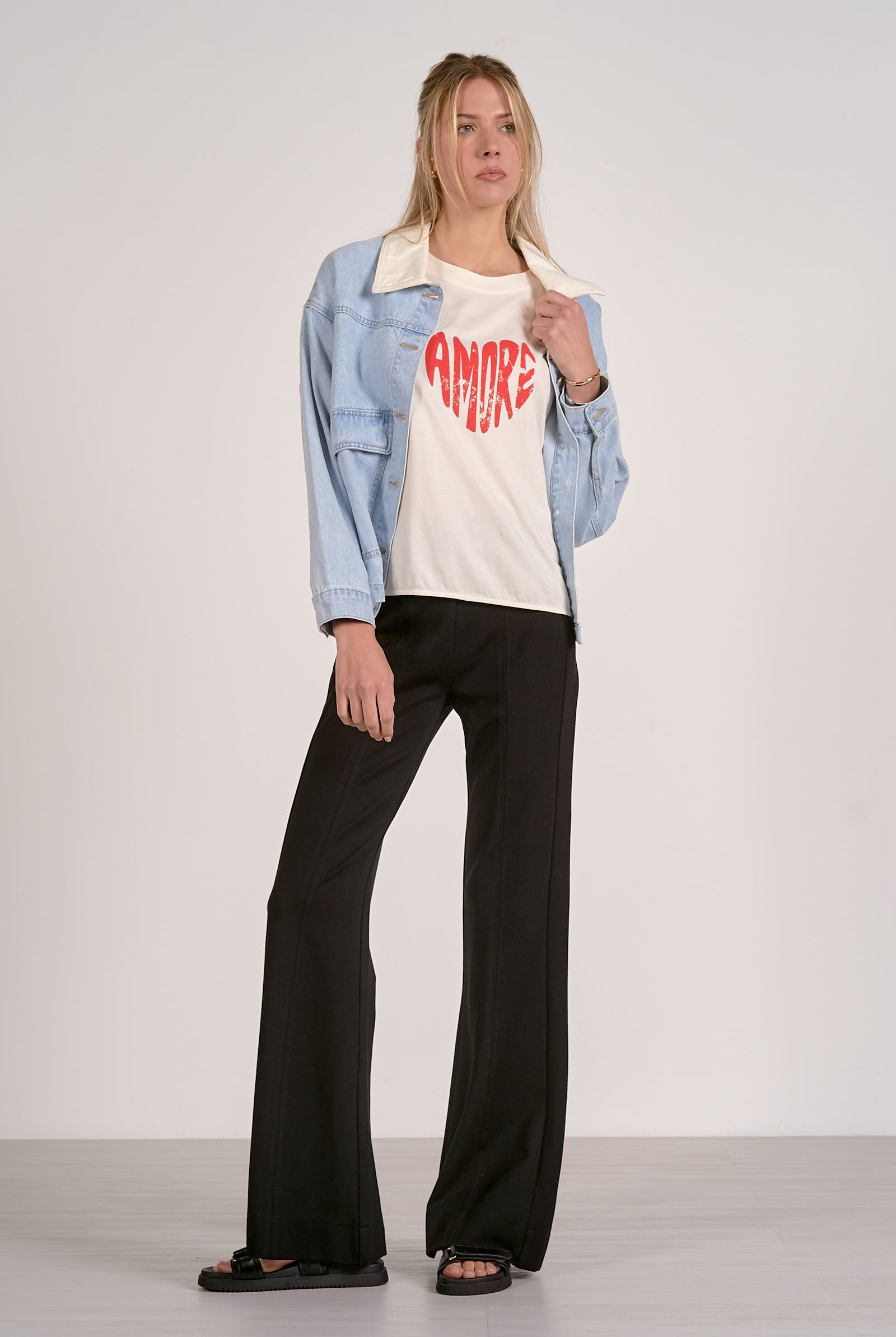 Full outfit view of light blue denim jacket styled with graphic tee and black pants.