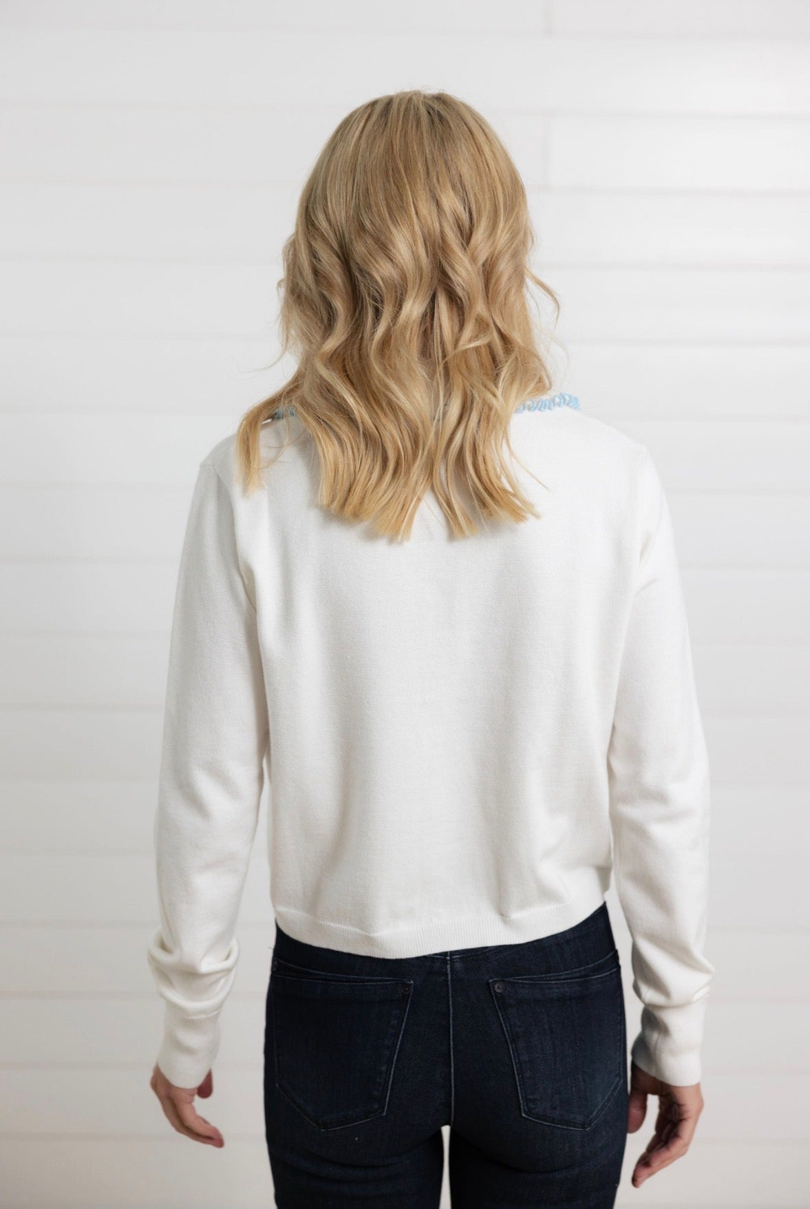 back of Mac and Me ivory ruffle collar sweater with blue lettuce trim worn with dark denim