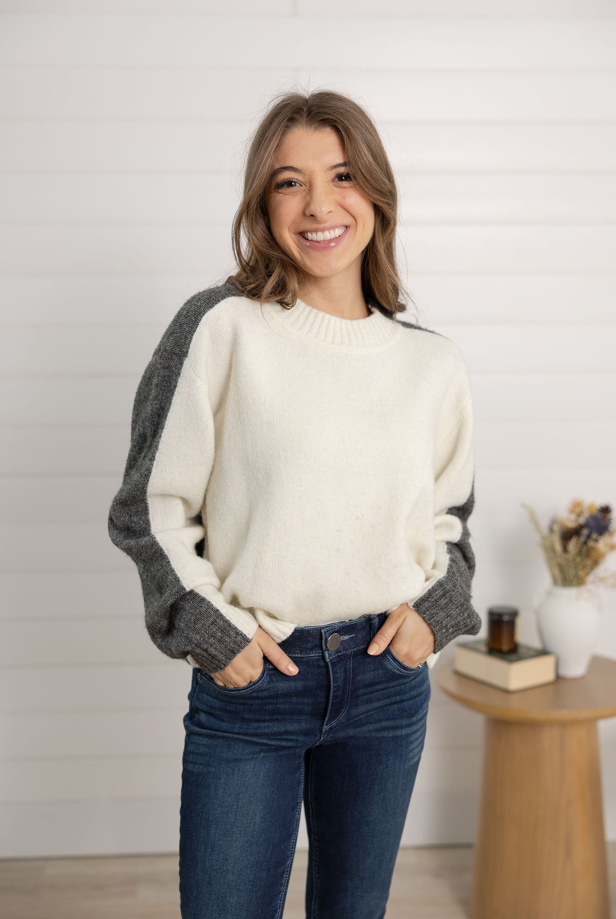 woman showing the front of the color block sweater in grey and white