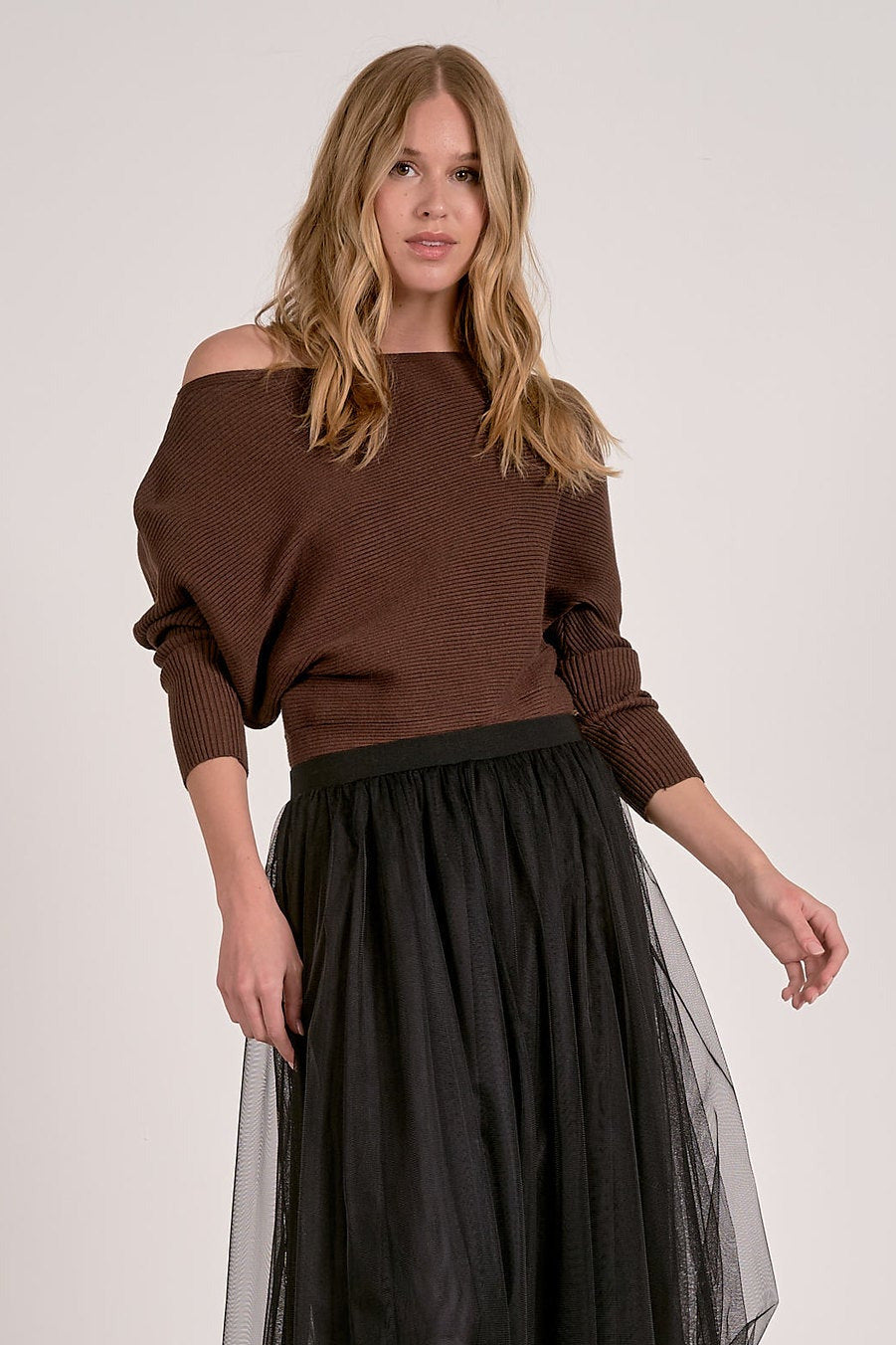 model wearing dark chocolate off shoulder ribbed sweater with dolman sleeves and black tulle skirt