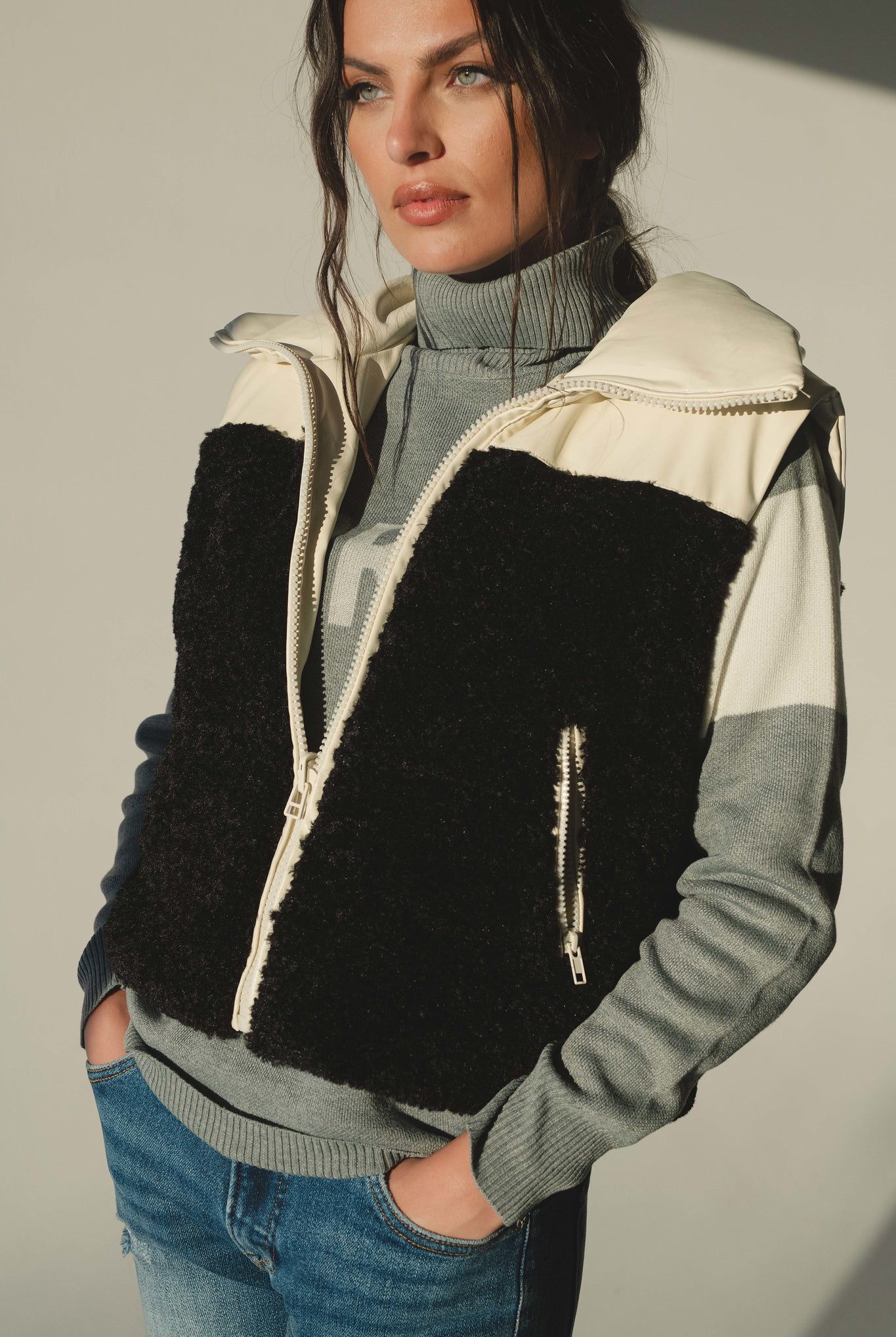 Woman wearing black and cream reversible sherpa vest with grey sweater