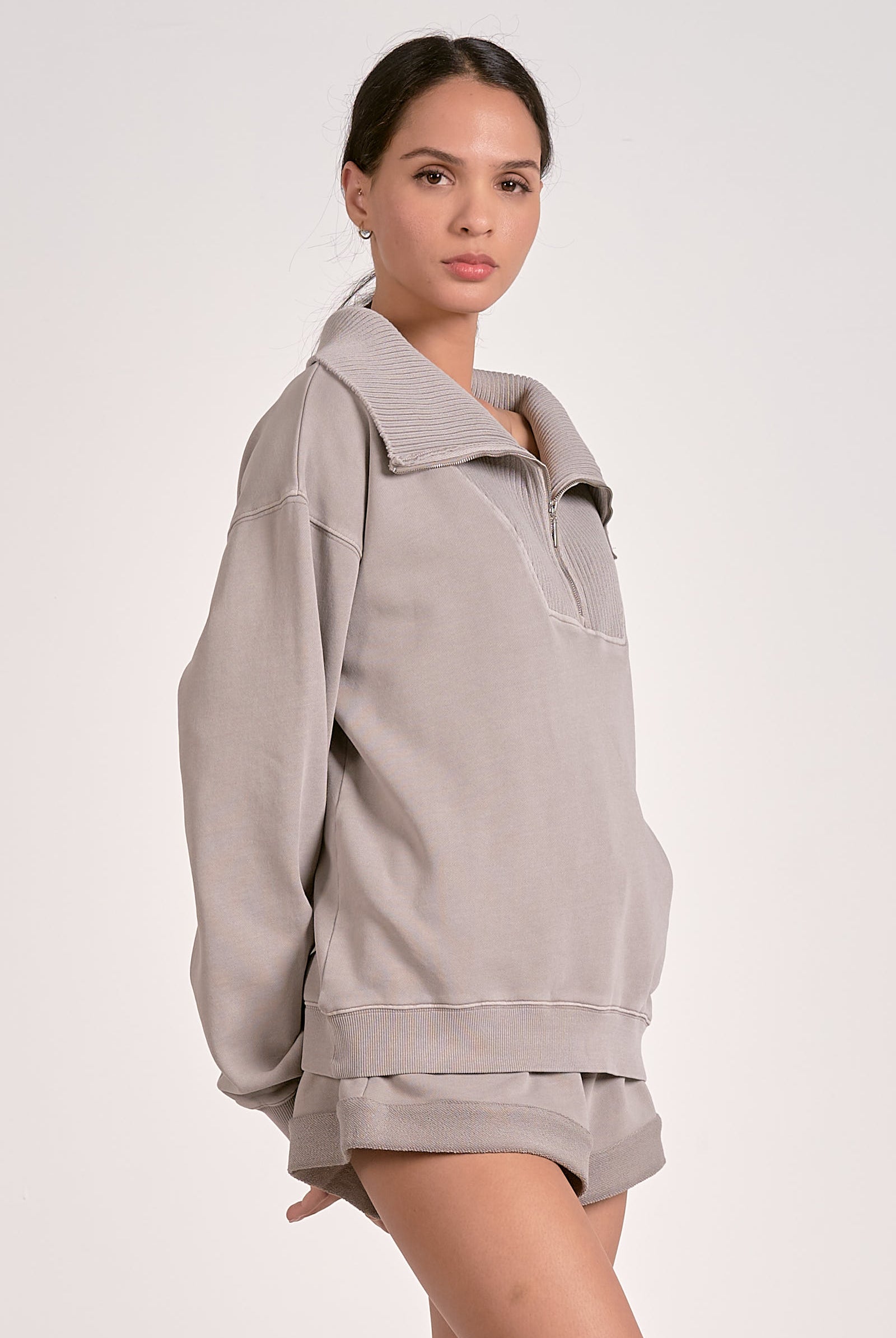 Model showing the side view of a quarter zip ribbed sweatshirt