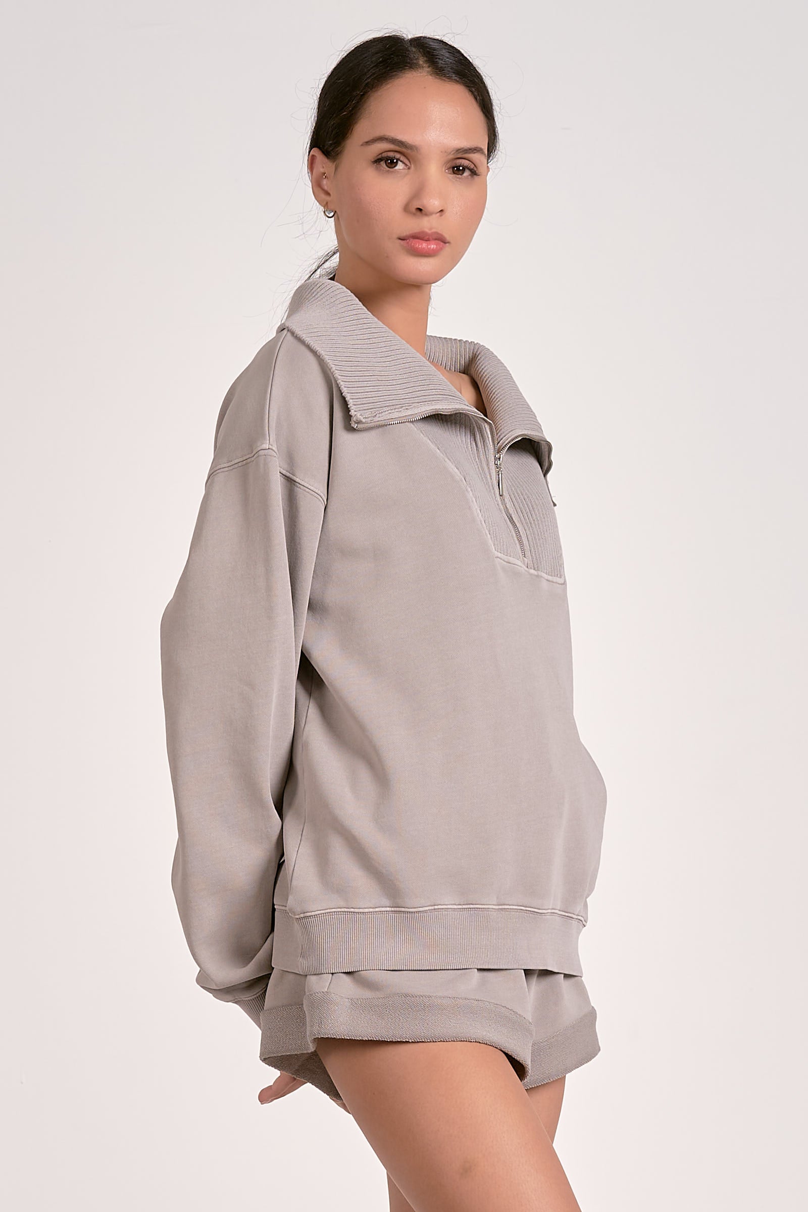 Model showing the side view of a quarter zip ribbed sweatshirt