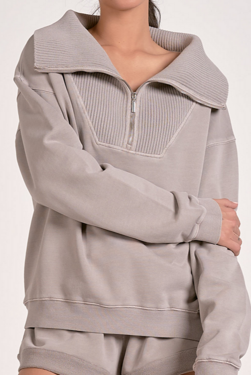 Woman showing a close up of a heather grey ribbed neck quarter zip sweatshirt