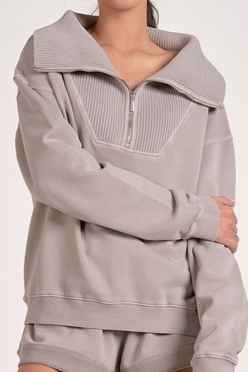 Woman showing a close up of a heather grey ribbed neck quarter zip sweatshirt