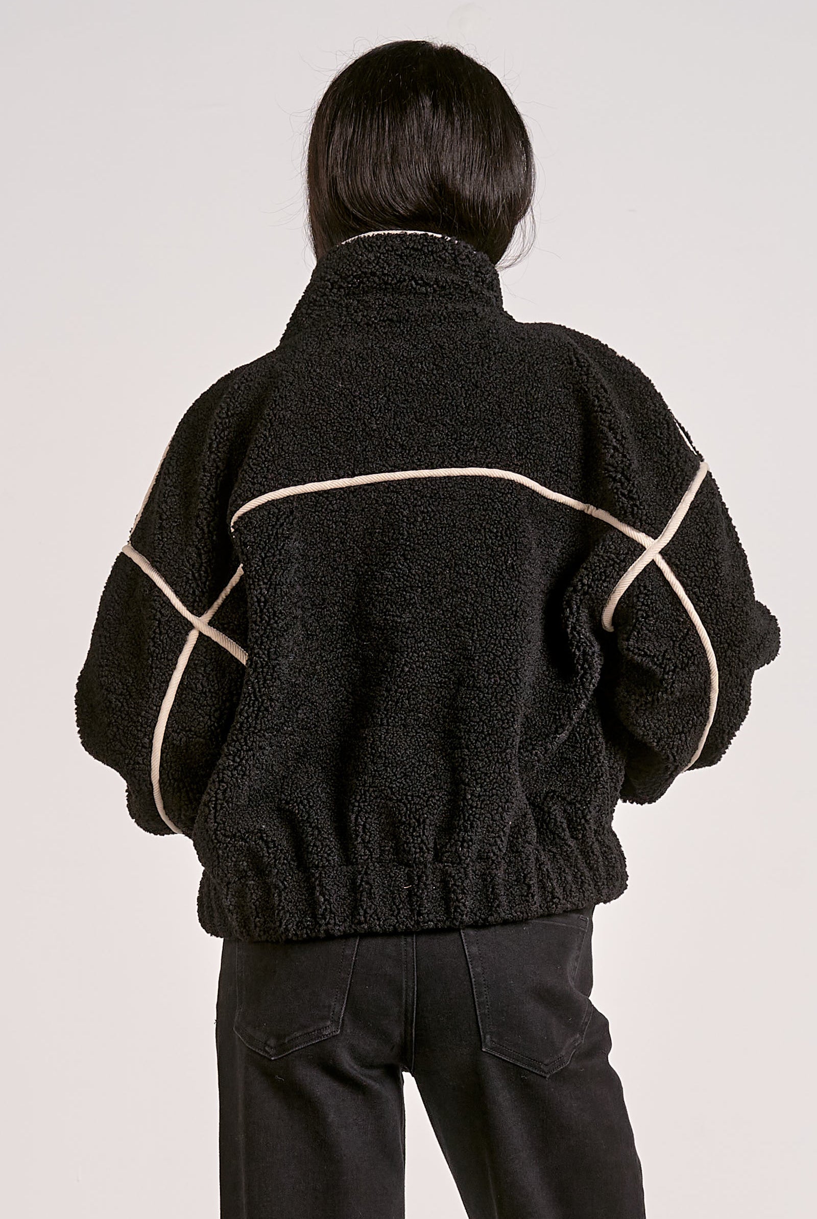 woman showing the back of the black sherpa bomber jacket with contrast trim