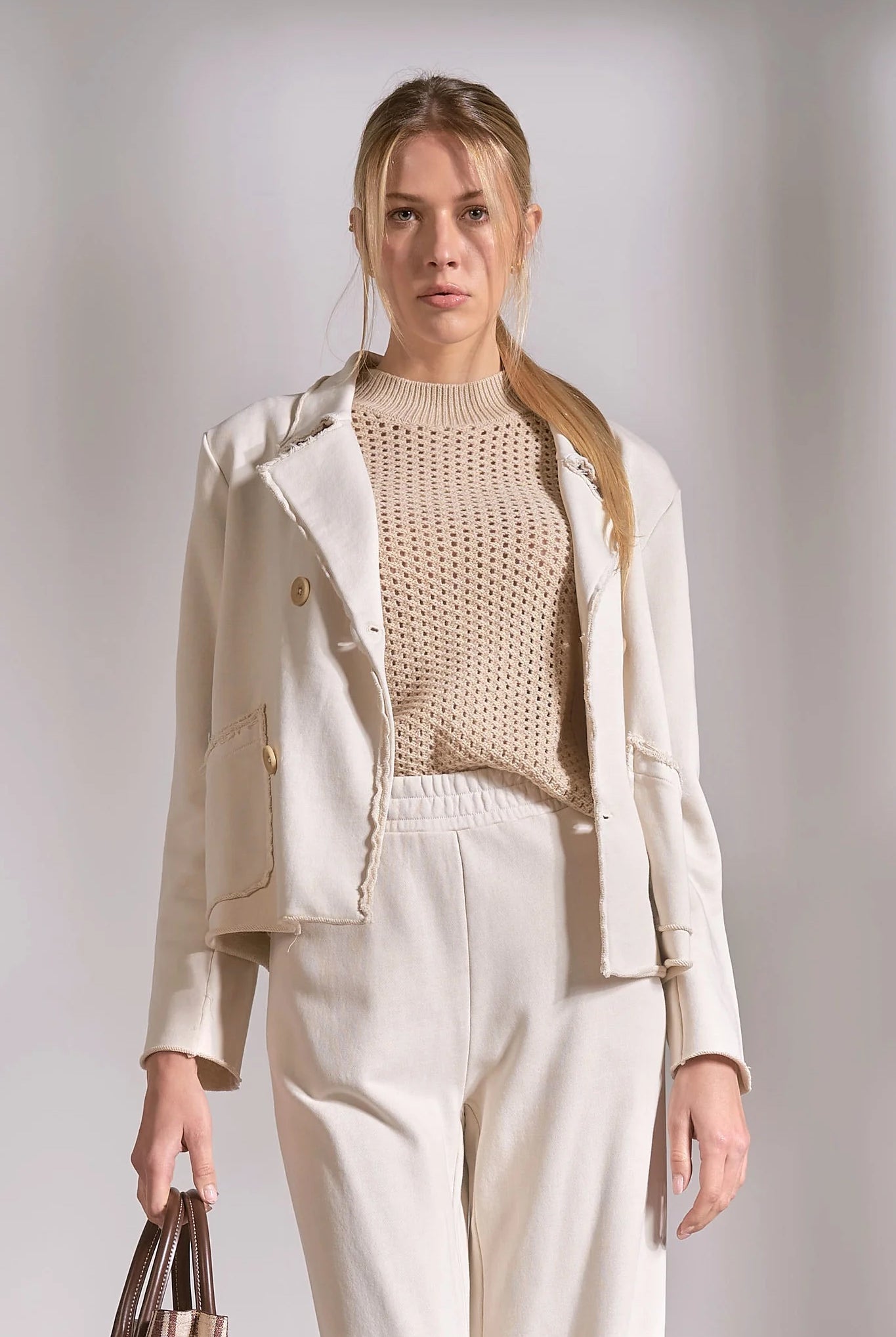 Stone knit blazer worn open with neutral sweater and trousers