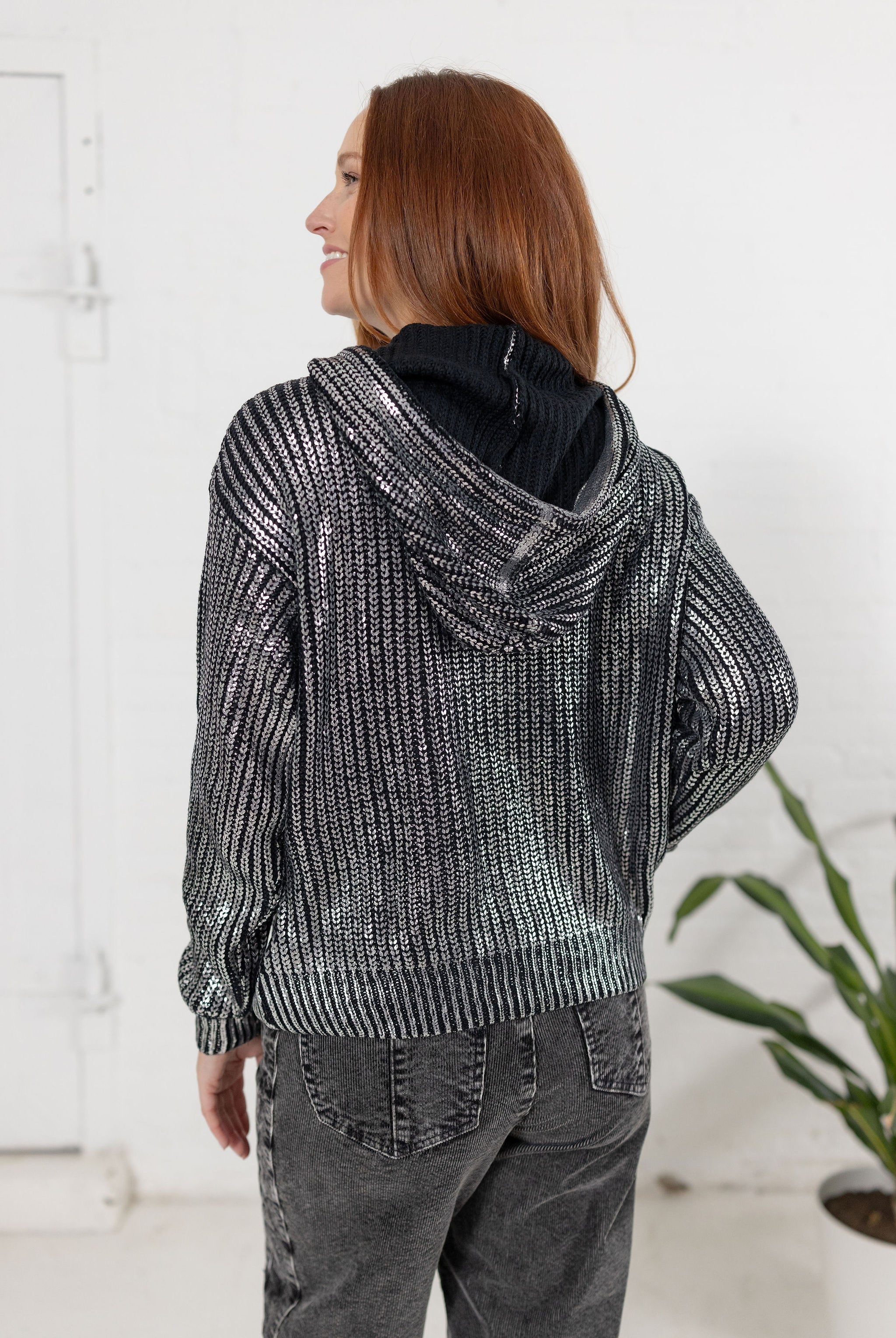Model showing the back of the metallic knit sweater in silver from Mainstream Boutique Bloomington