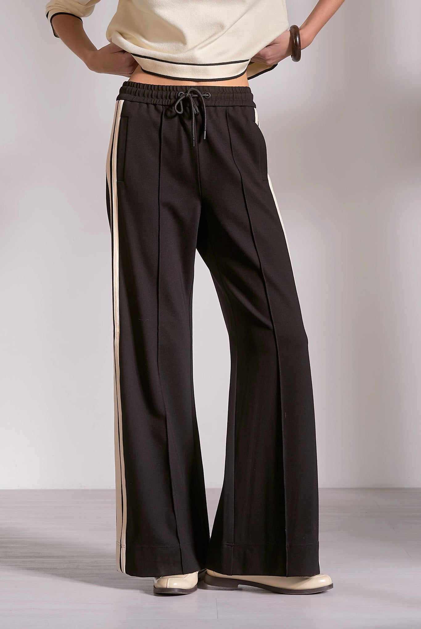 Black wide leg track pants with natural stripe and drawstring waist