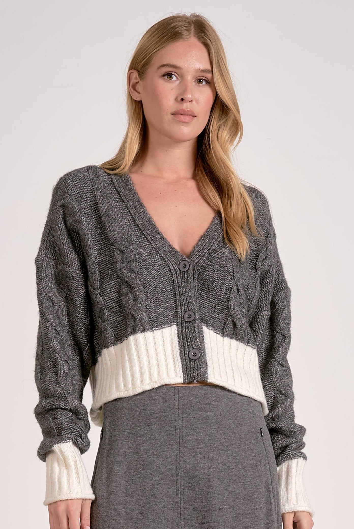 Front view of the grey and white two-tone cropped v-neck cardigan with cable knit and button front