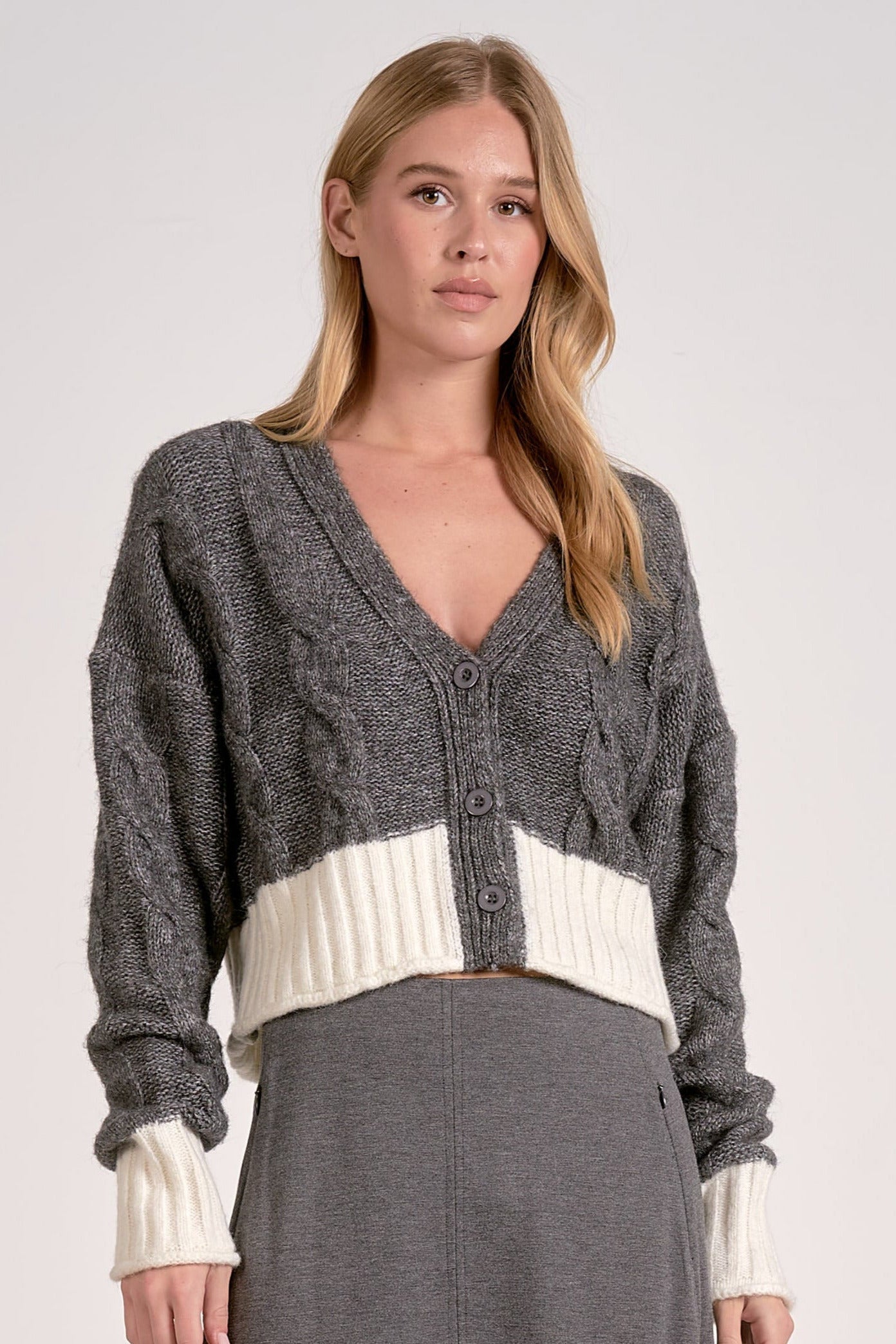 Front view of the grey and white two-tone cropped v-neck cardigan with cable knit and button front