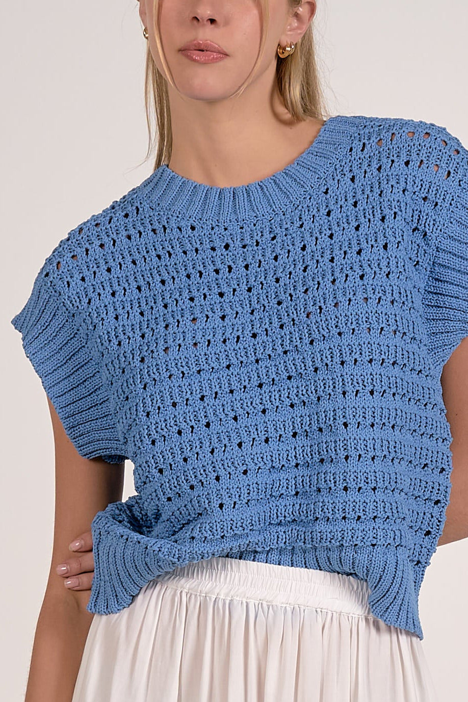 close up details on vibrant blue textured open knit cap sleeve sweater with ribbed trim