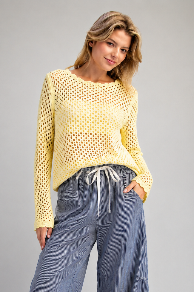 Woman wearing yellow open knit sweater and blue striped pants