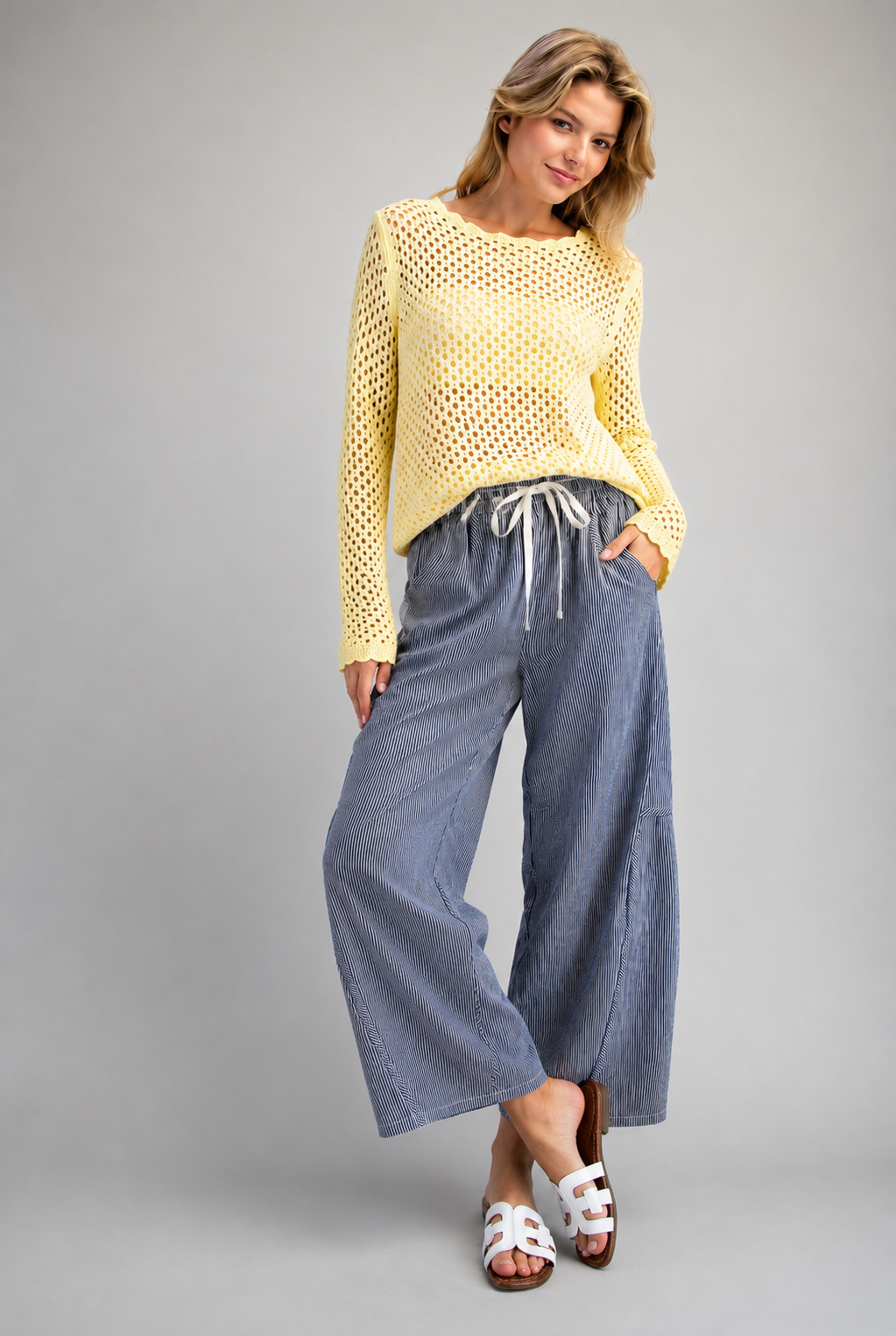 Woman wearing yellow open knit sweater and blue striped drawstring pants