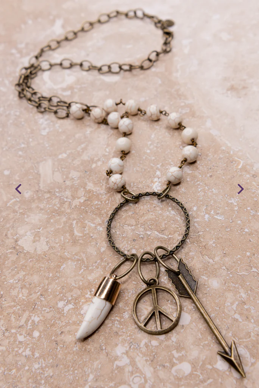 long necklace with white beading and charms on a circular dangle